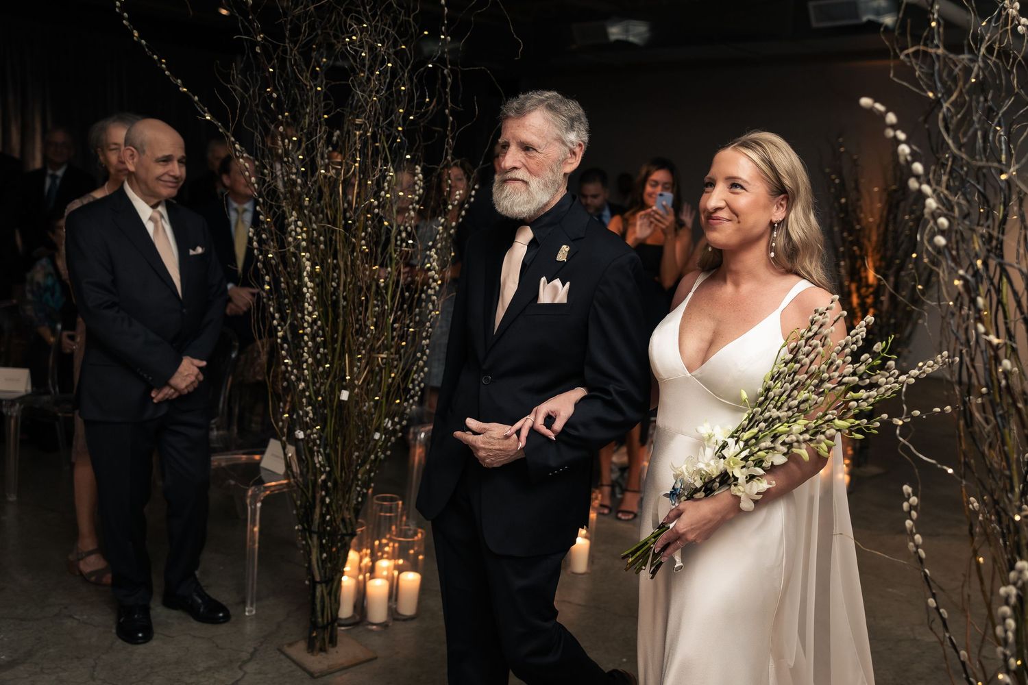 A wedding reception with guests mingling under glowing string lights and elegant decor.