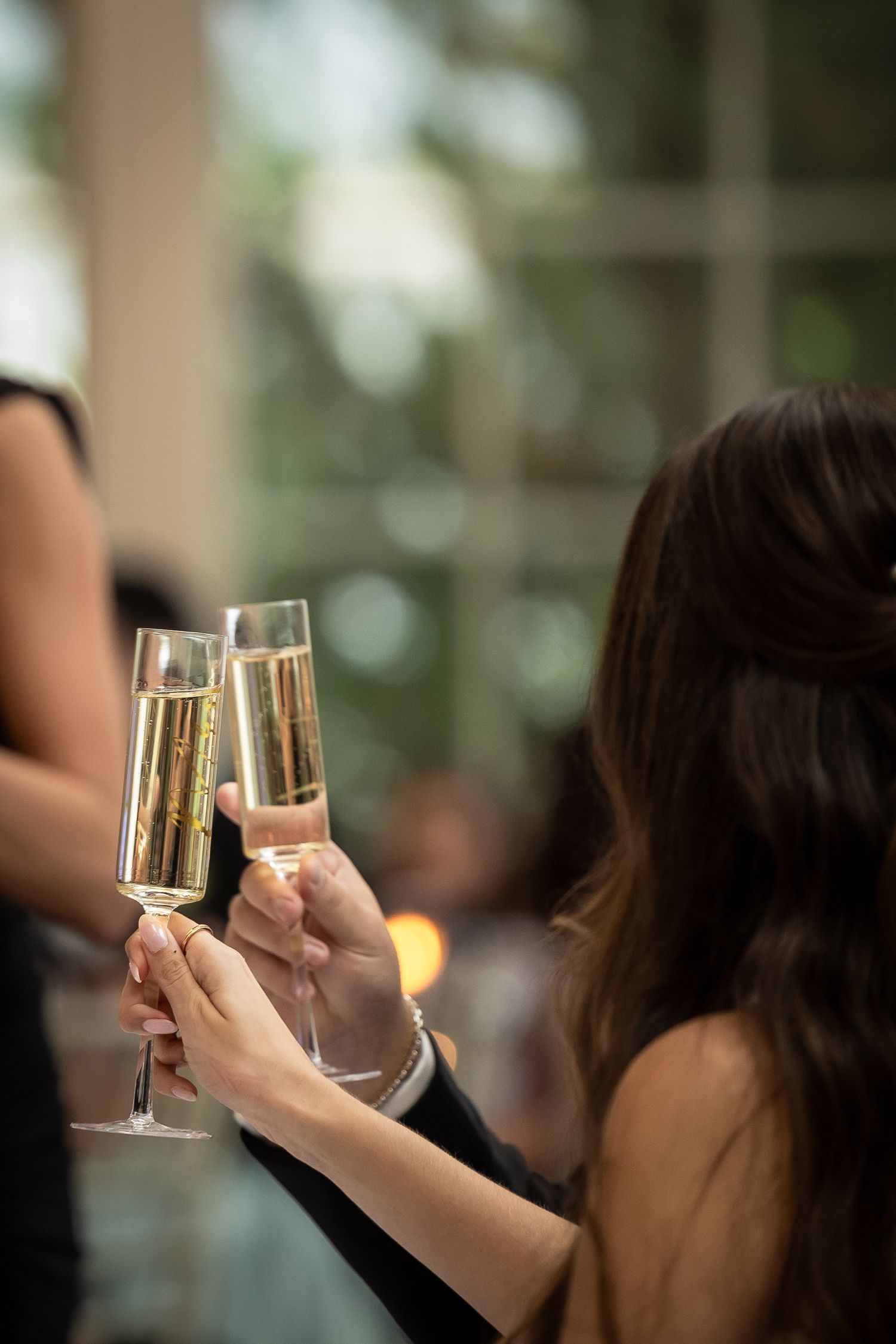 Wedding guests raise champagne glasses for a celebratory toast.