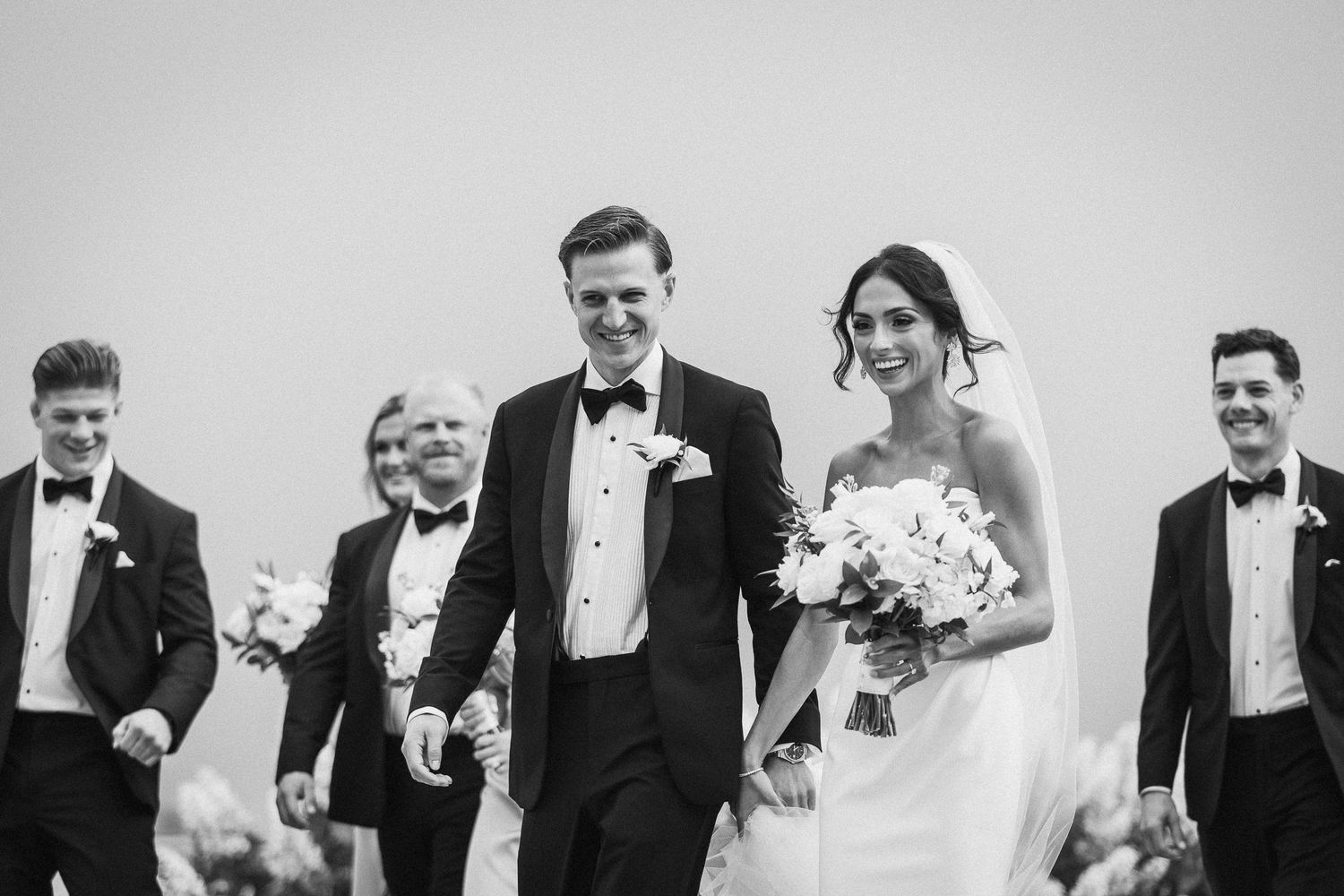 Black and white candid moments of wedding party during outdoor celebration.