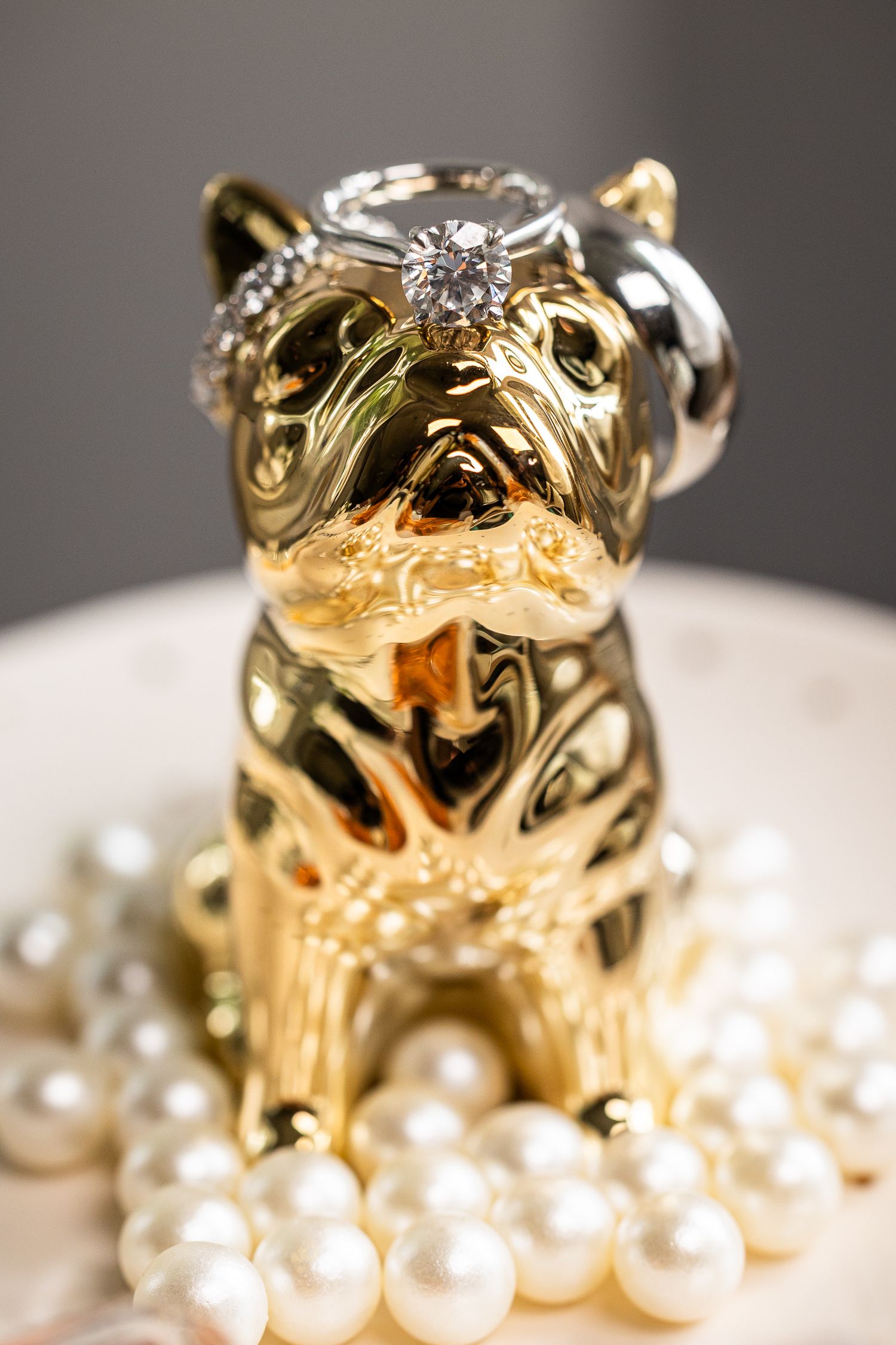 A golden bulldog charm rests elegantly among white pearl beads in a luxurious jewelry setting.