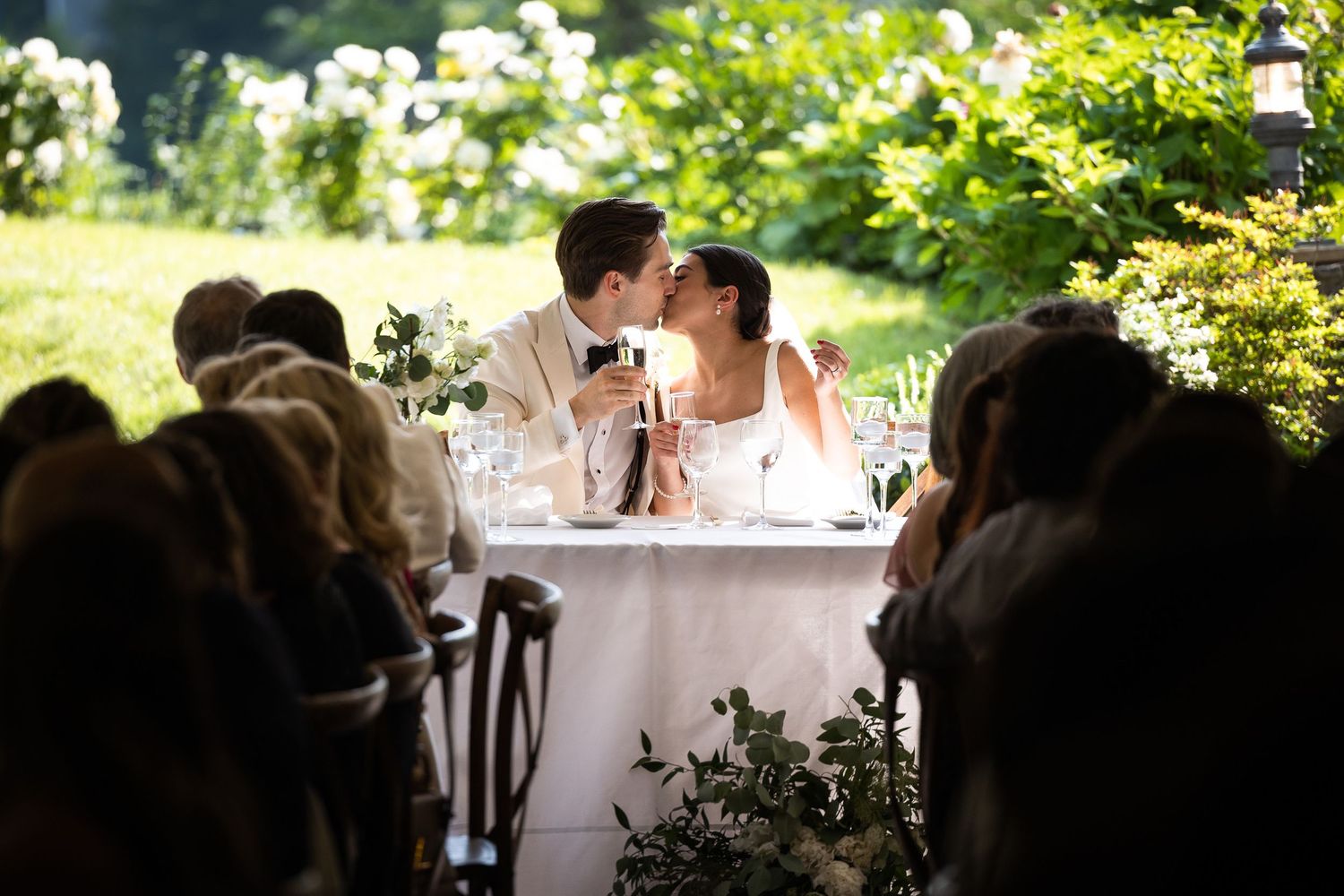 Couple shares an intimate moment at their reception table surrounded by guests.
