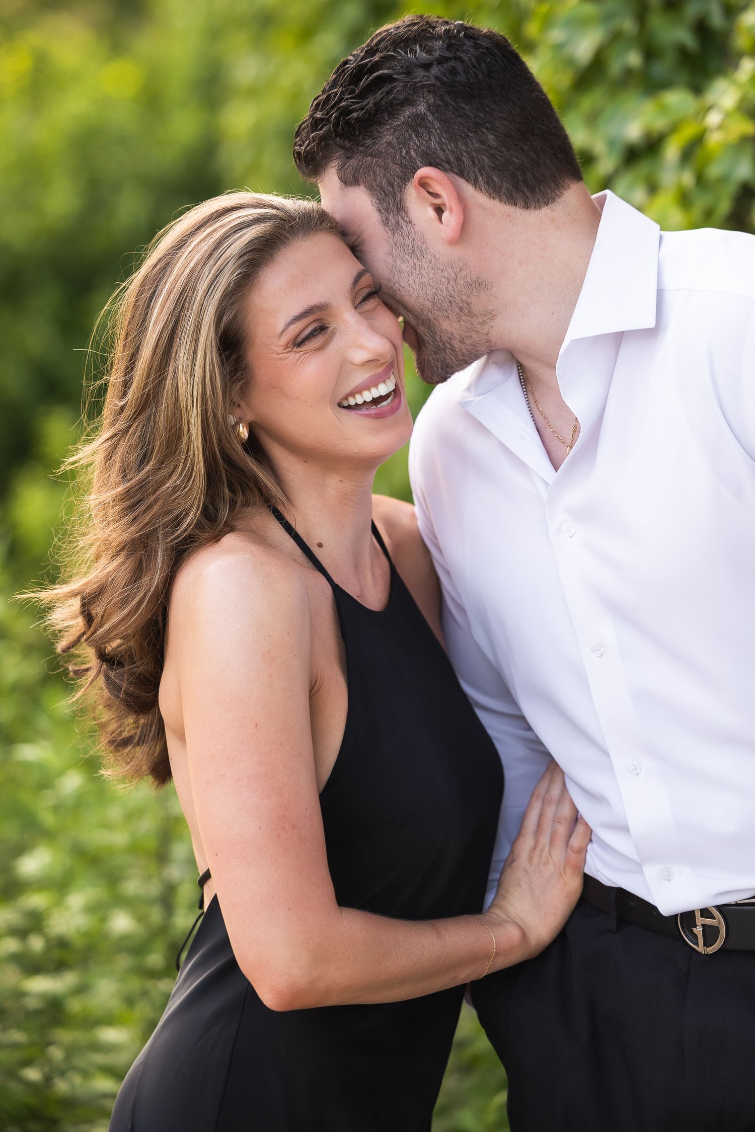 A joyful couple sharing an intimate moment while embracing in a garden setting.