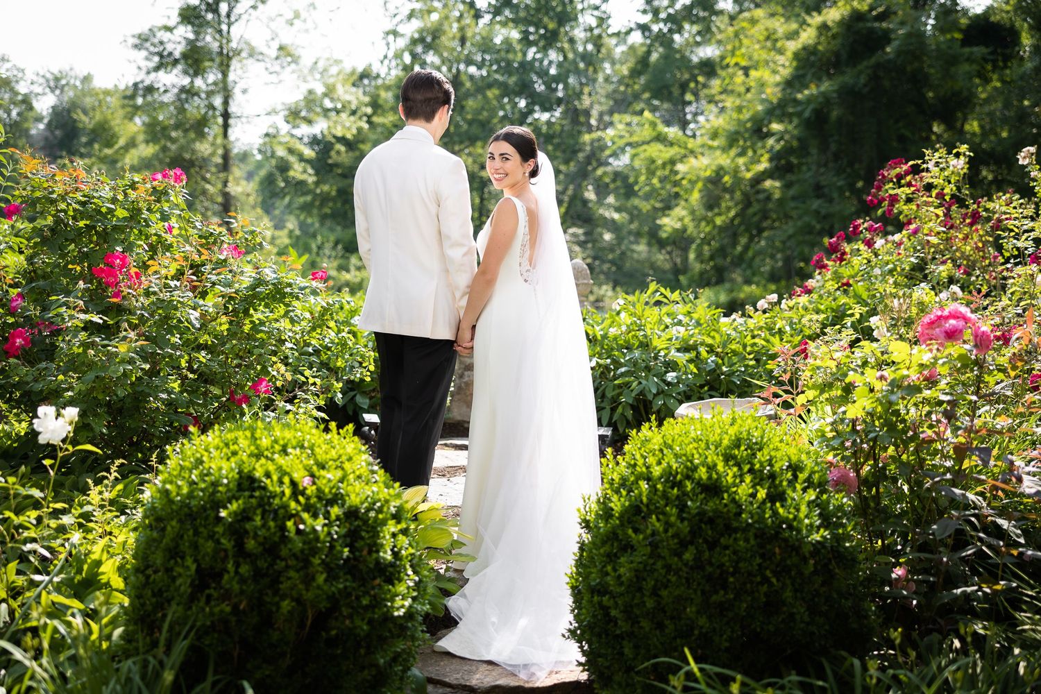 Newlyweds walking together through a vibrant garden landscape.