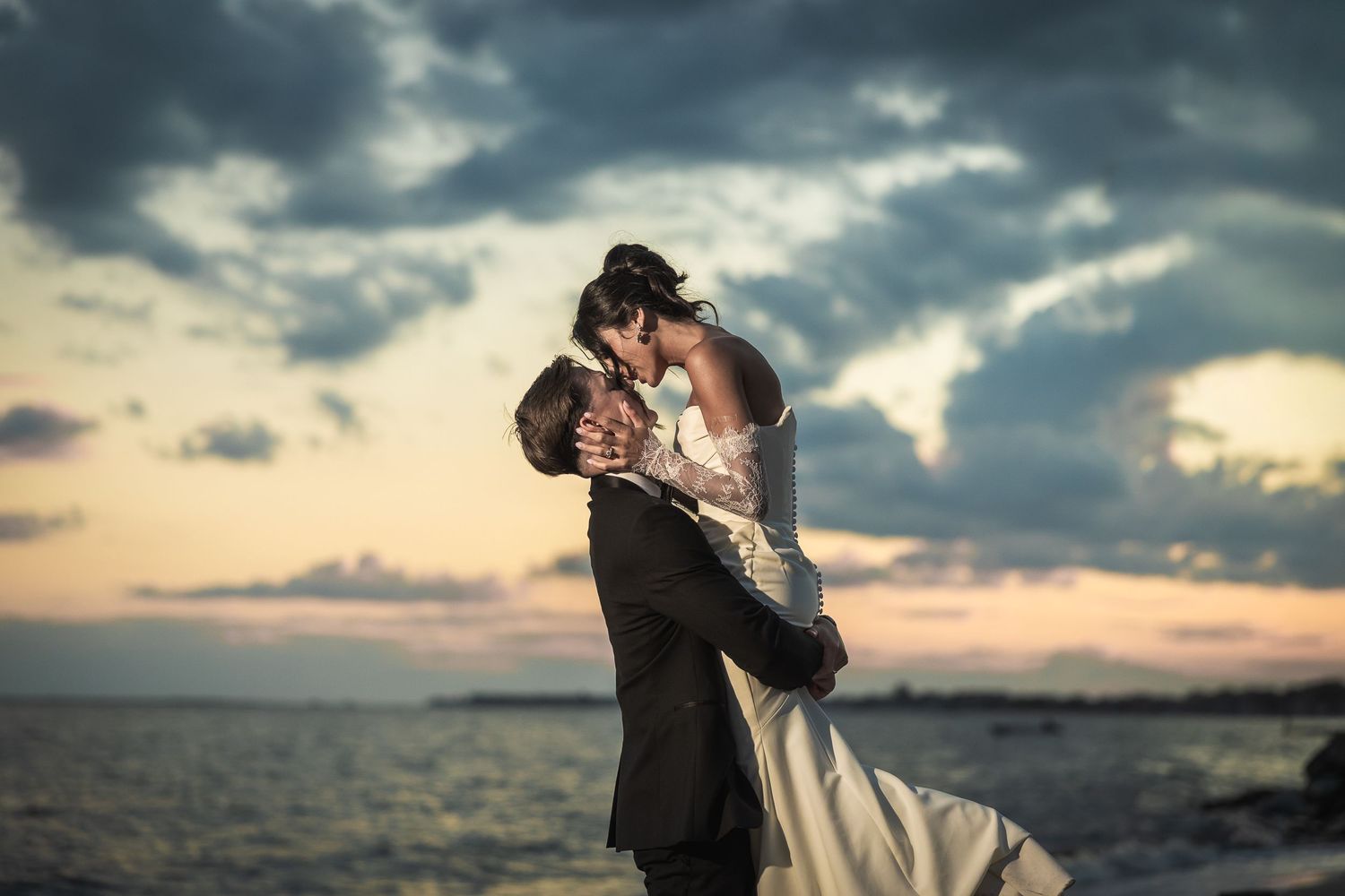 Dramatic sunset wedding portraits with cloudy sky over ocean.