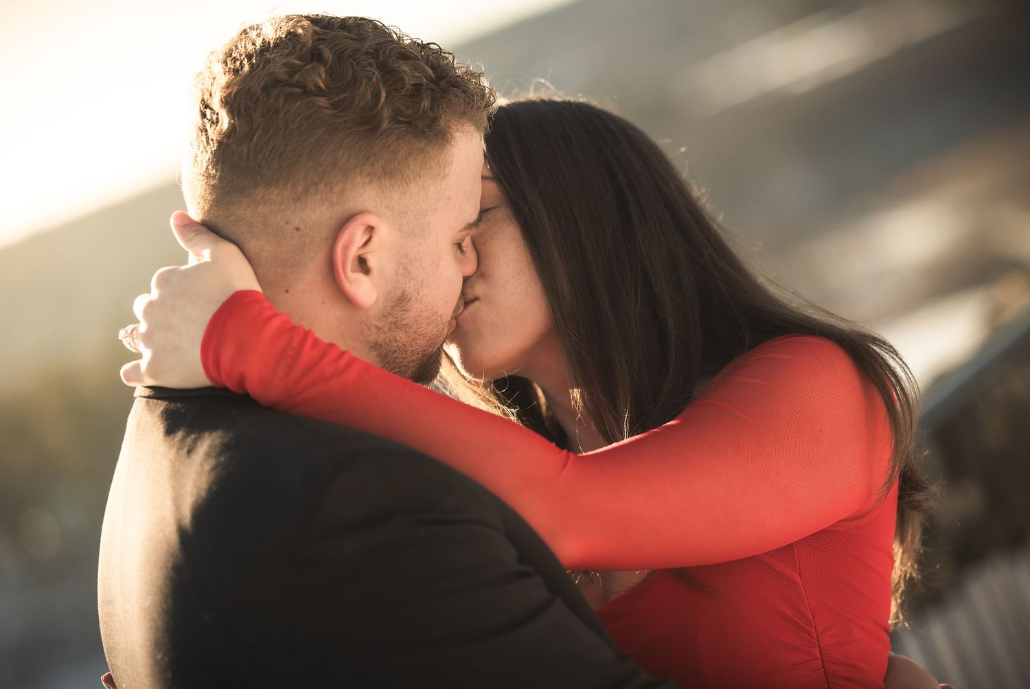 An intimate embrace between a couple, with one wearing red and the other in black.