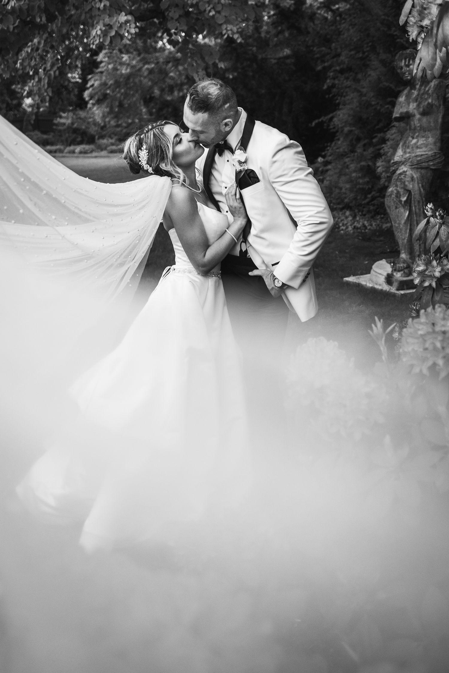 Romantic black and white wedding photos with dreamy fog effect in garden setting.