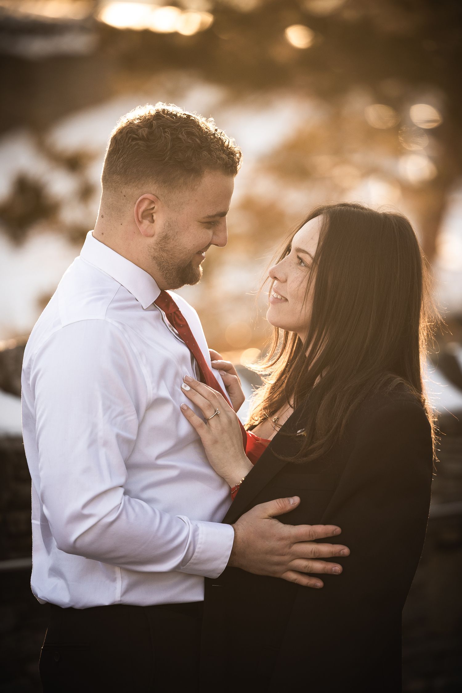 A romantic couple embraces in warm sunset lighting during an intimate outdoor photo session.
