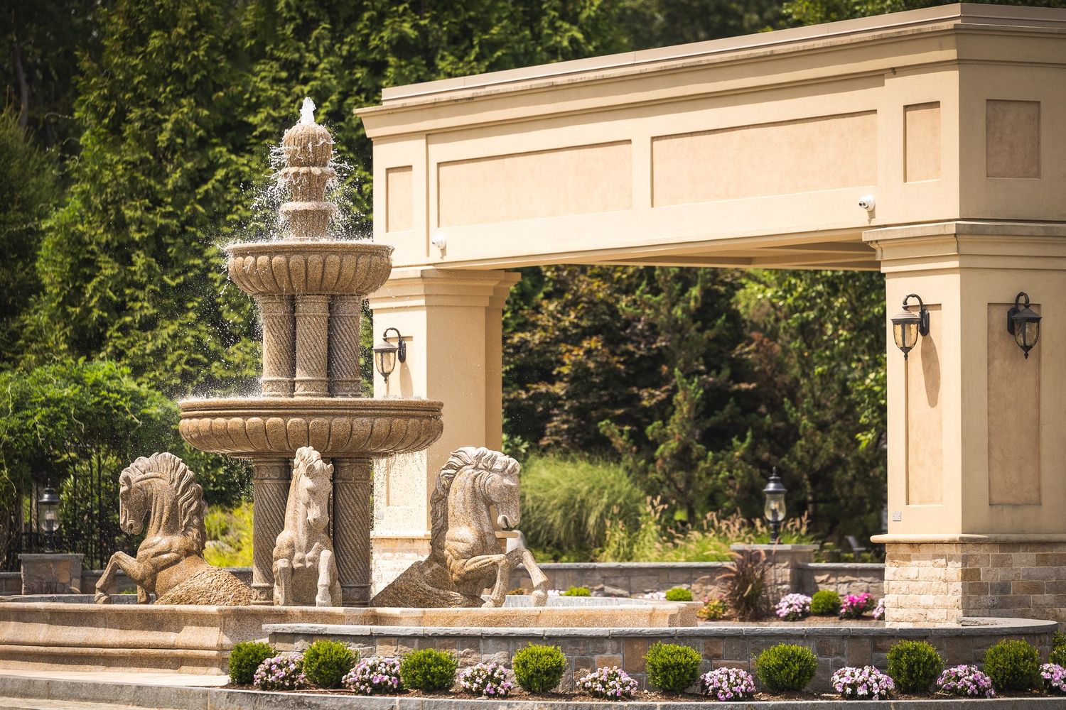 Elegant stone archways and columns line a garden walkway with lush greenery and classical architectural details.