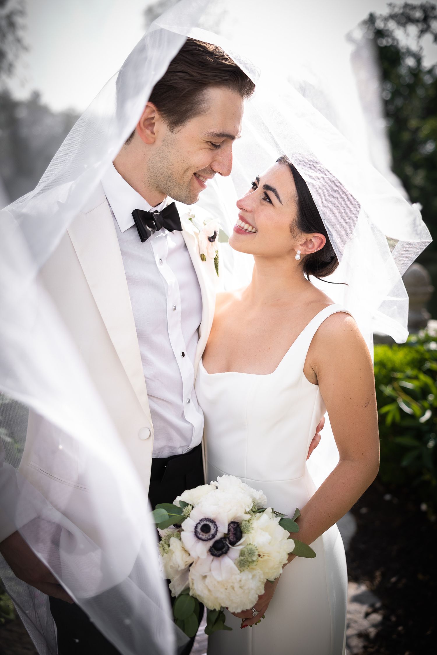 A joyful wedding moment captured as the couple shares a laugh under a flowing veil.