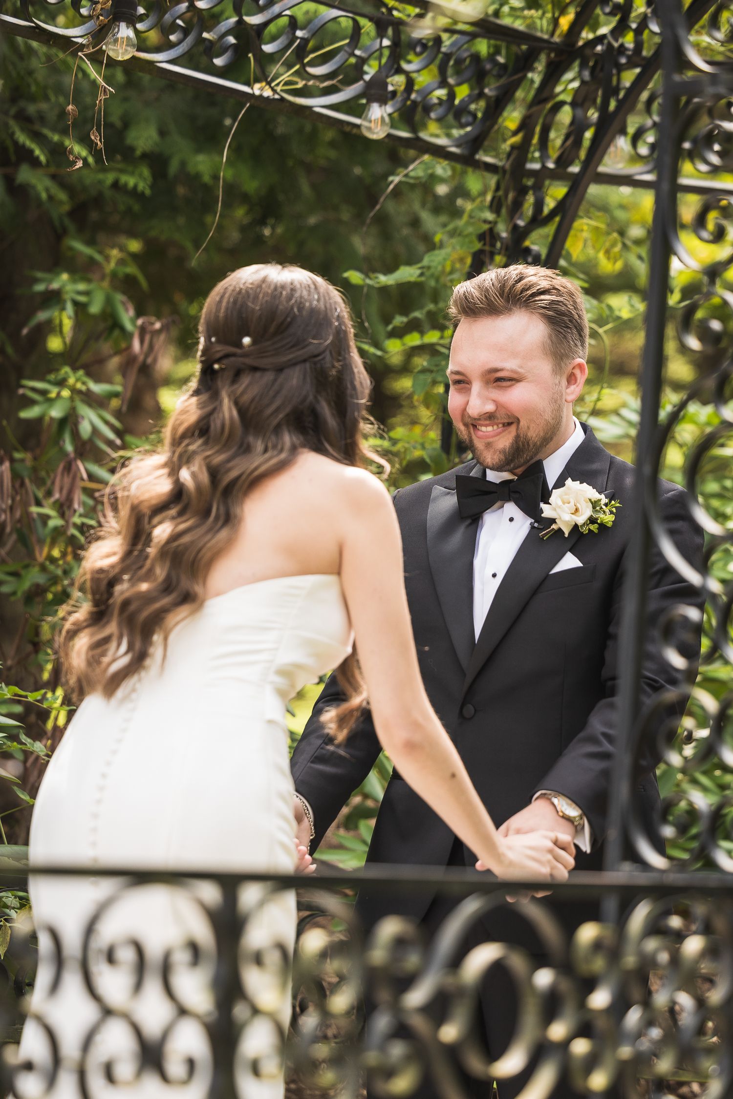 Romantic first look moment between newlyweds in a lush garden setting.
