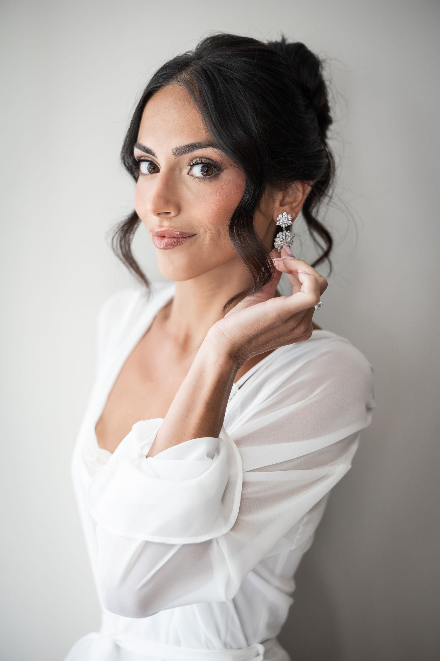 Elegant bridal portrait series showing preparation moments in a white robe against neutral background.