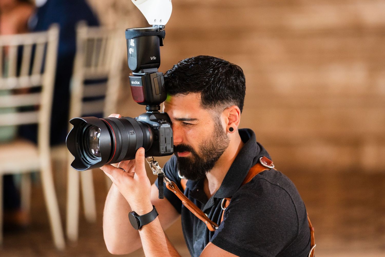 Professional photographer using DSLR camera with flash at indoor event.