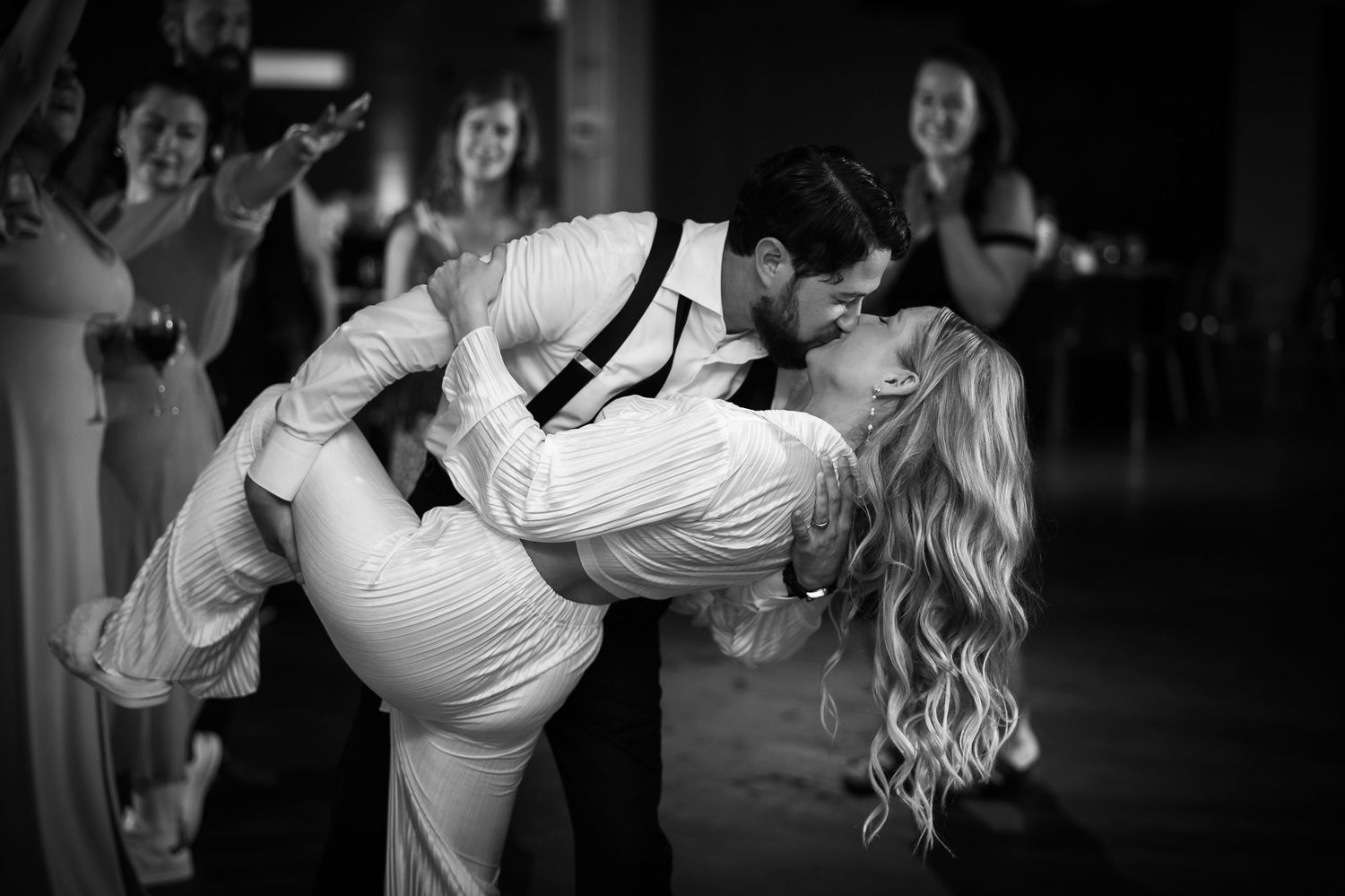 A couple performs an elegant dance move at what appears to be a wedding reception or formal event.