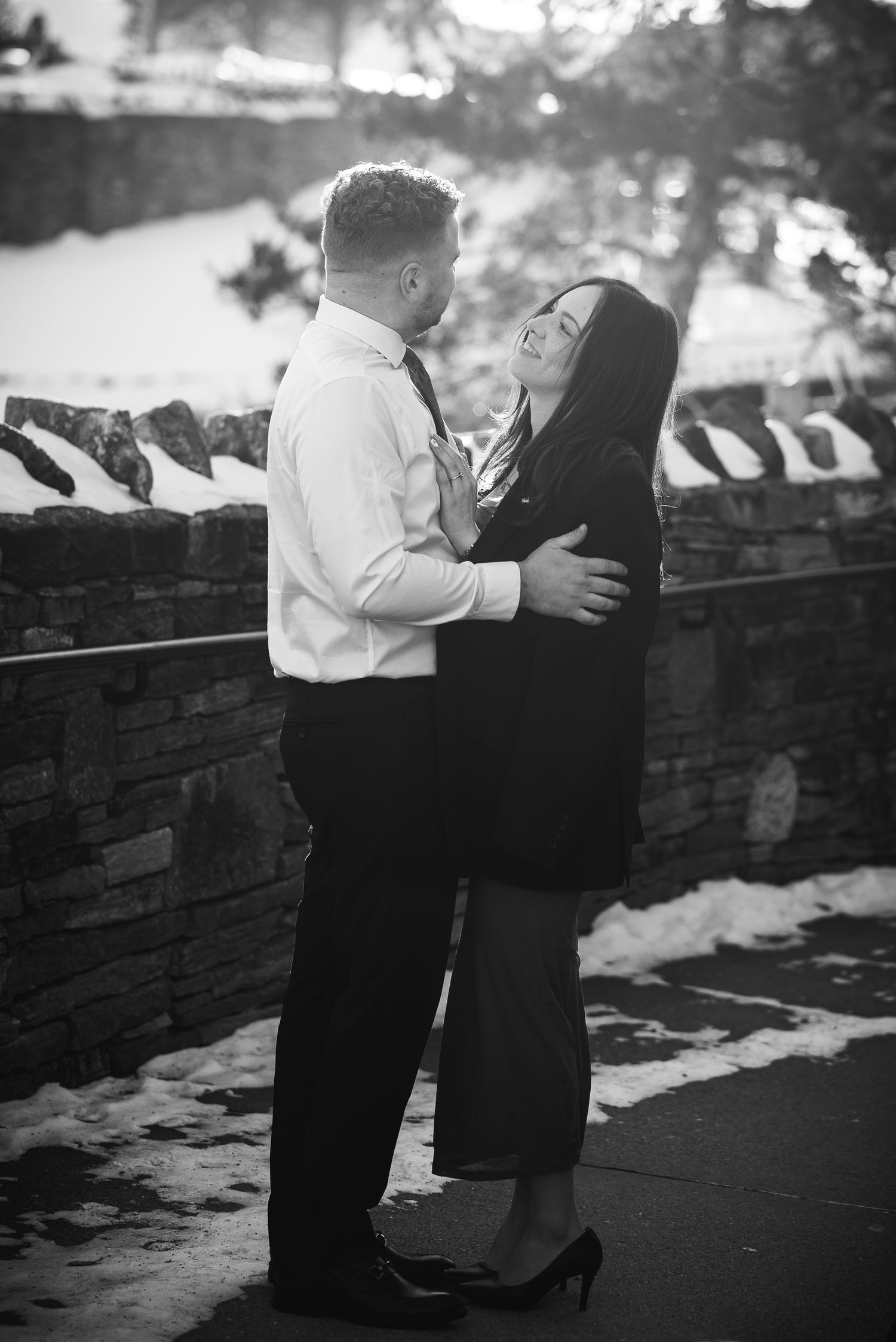Black and white photo sequence showing a tender moment between two people on a stone wall in a park setting.
