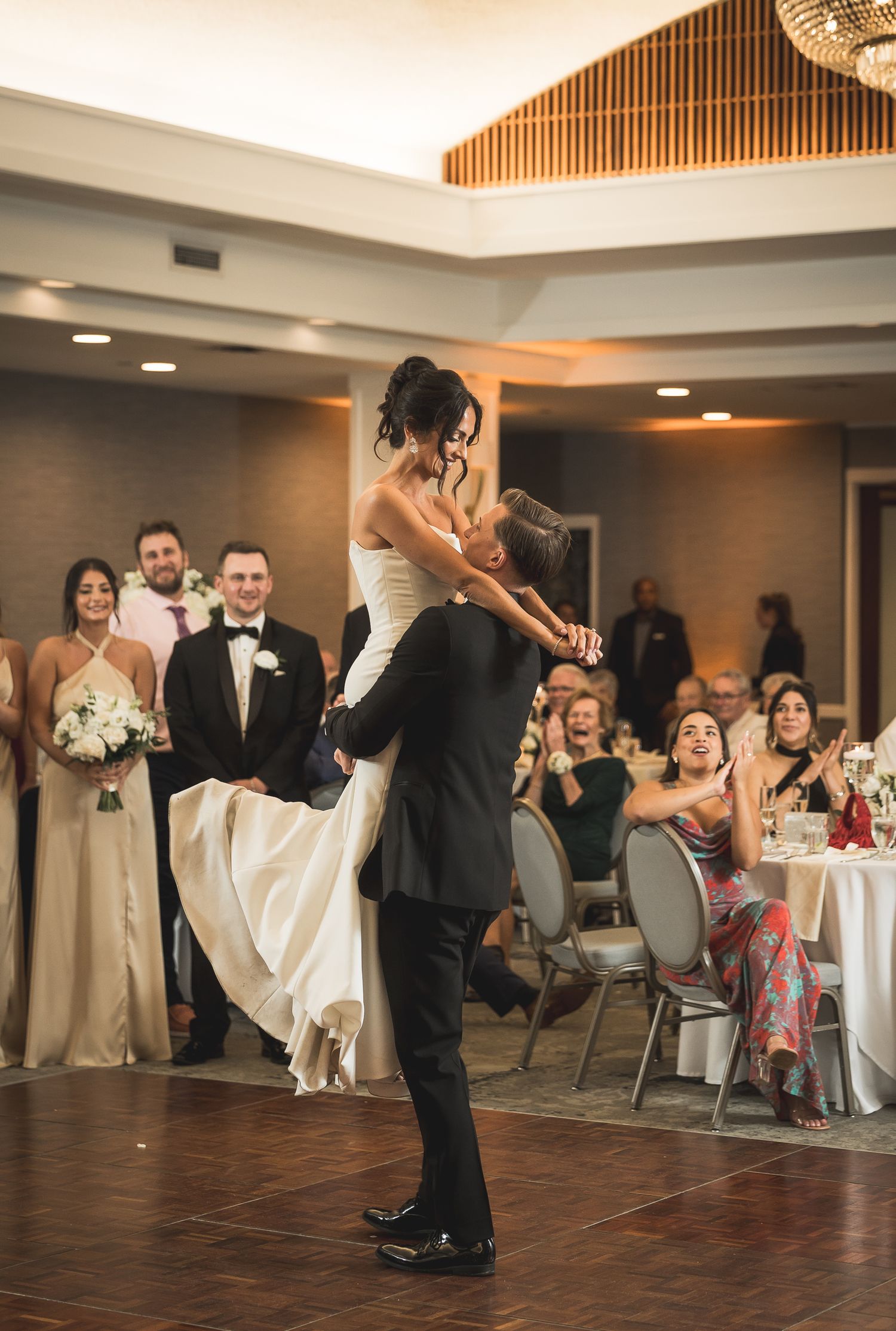 Romantic first dance at wedding reception with couple performing dramatic lift.