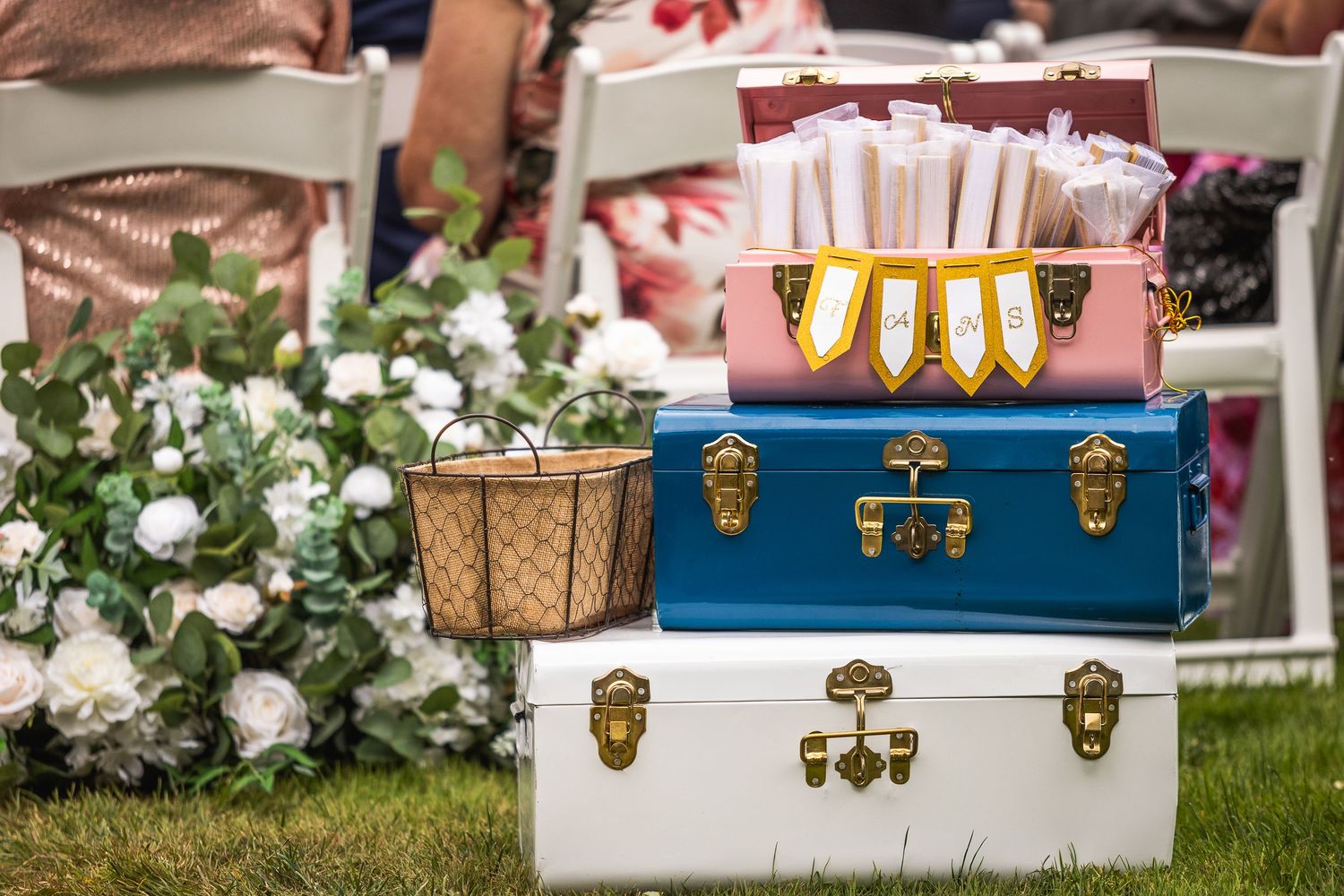 Vintage style suitcases and decorative trunks arranged as wedding decor on grass.