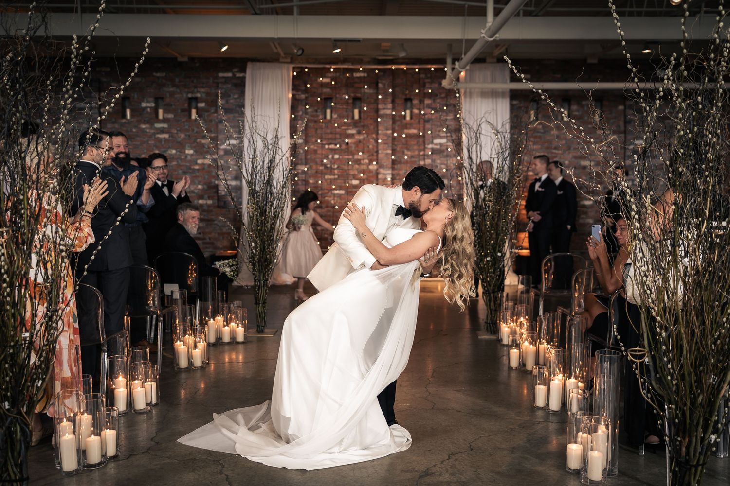 Romantic wedding ceremony aisle decorated with glowing candles and illuminated tree branches creating magical ambiance.