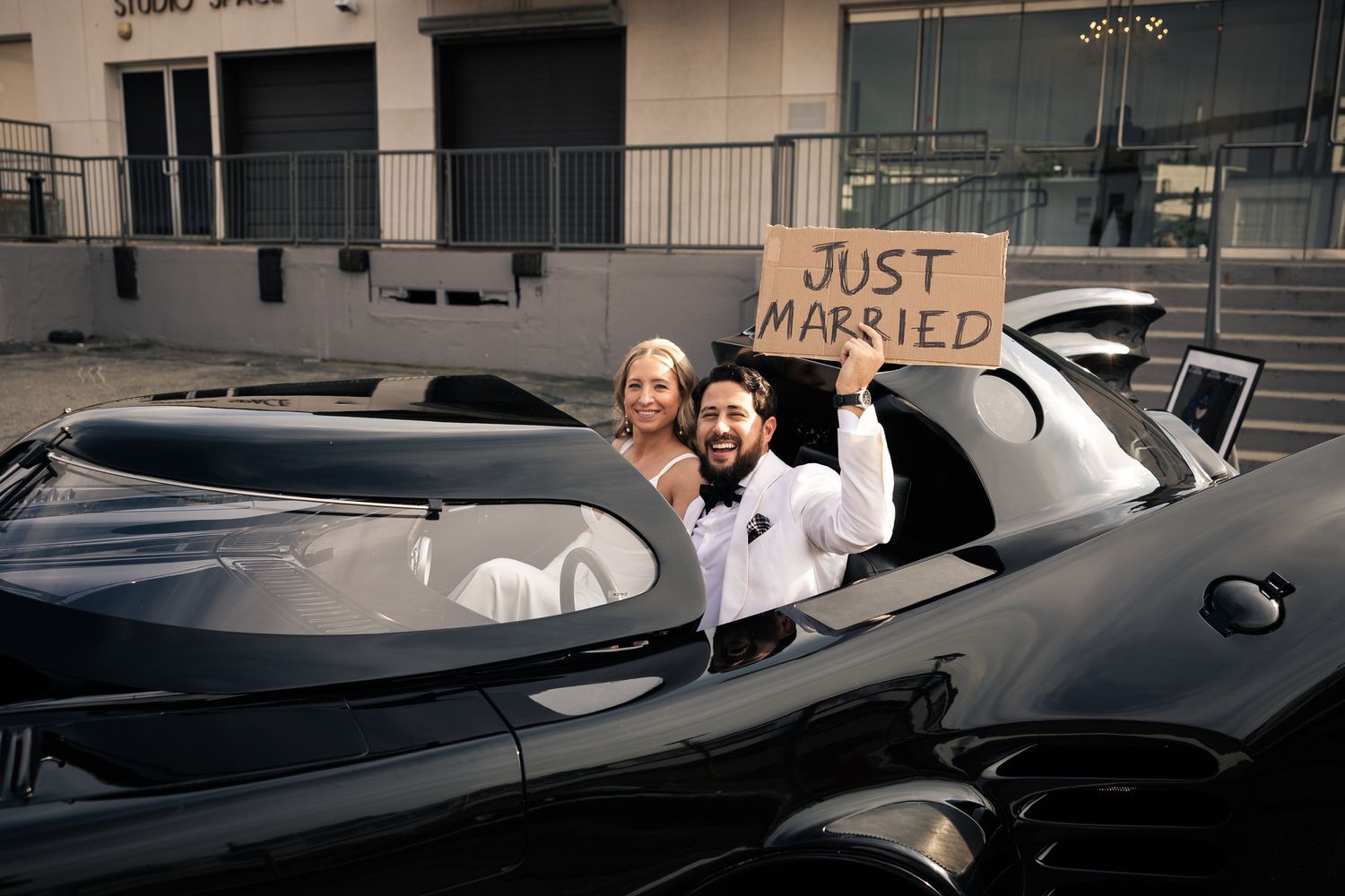 Newlyweds celebrate in luxury convertible with Just Married sign.