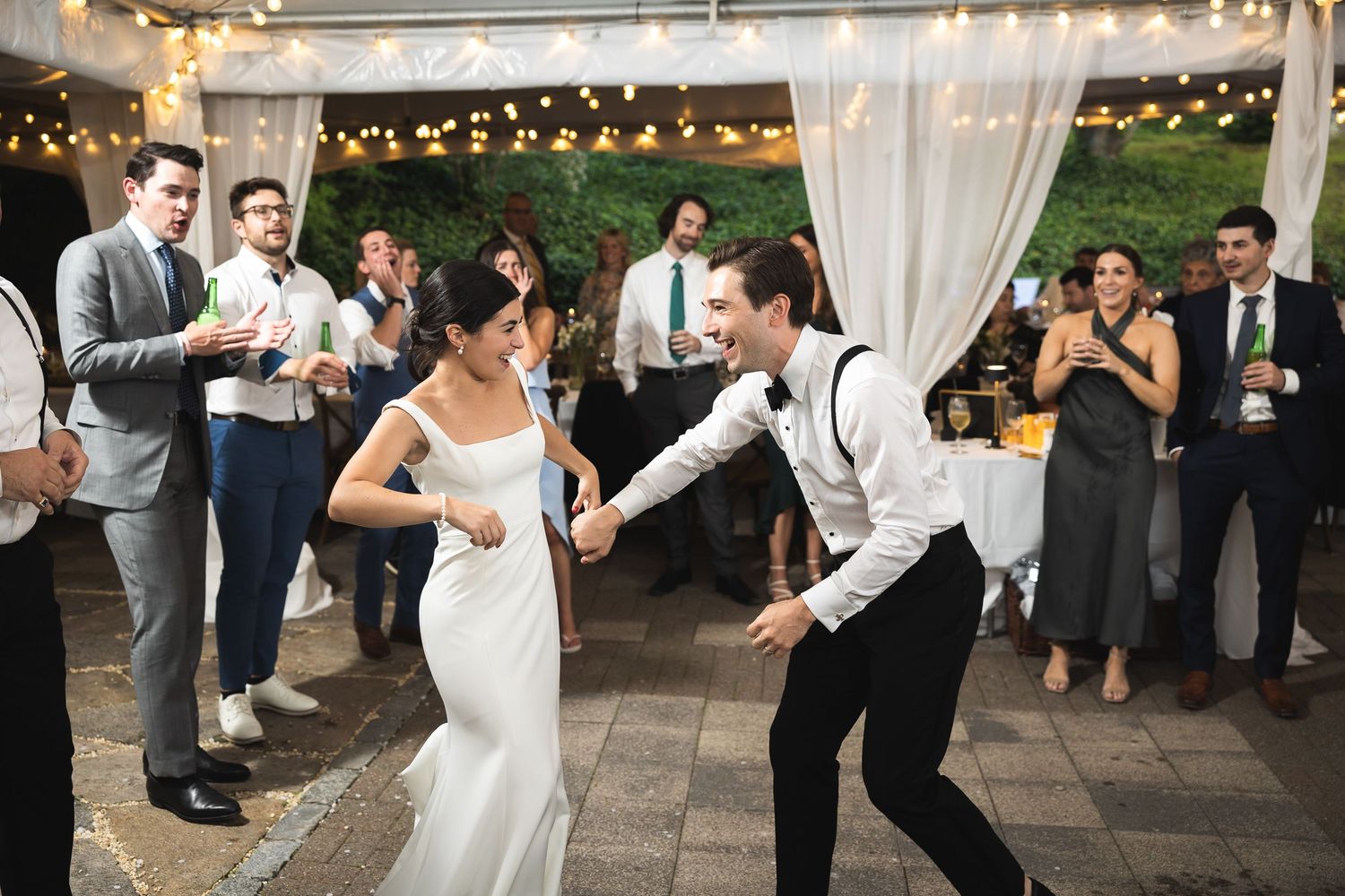 Wedding reception dance floor filled with guests celebrating under string lights.