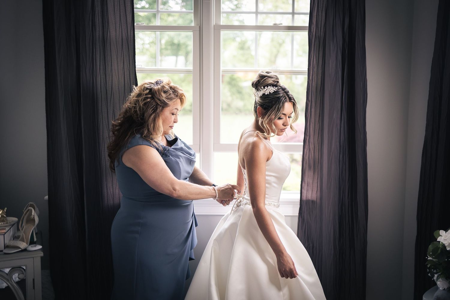Wedding preparation moments captured through window light in elegant interior setting.