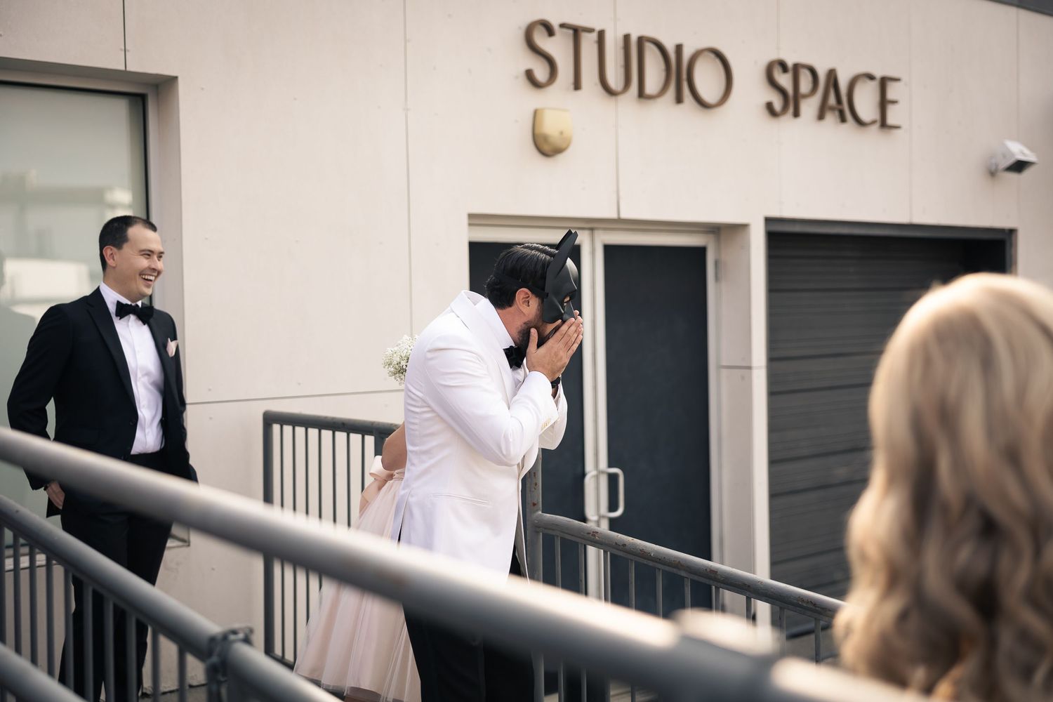 A group of formally dressed people gather outside a studio space entrance.