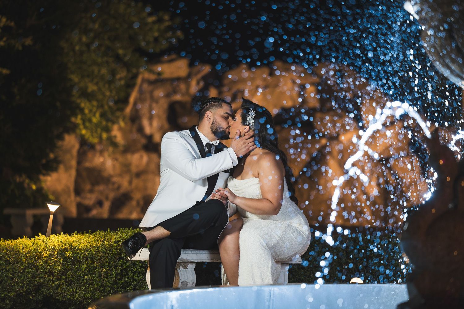 A couple embraces during a romantic moment with sparklers creating magical light trails in the background at dusk.