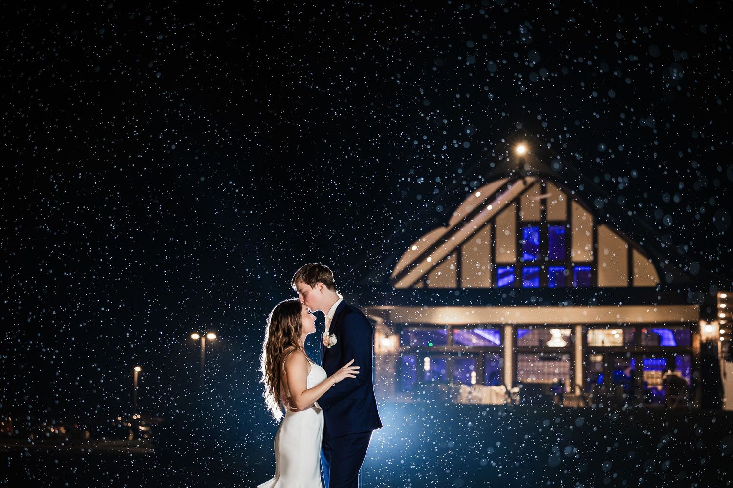 Silhouetted couple dancing together at night with blue-lit building in the background.