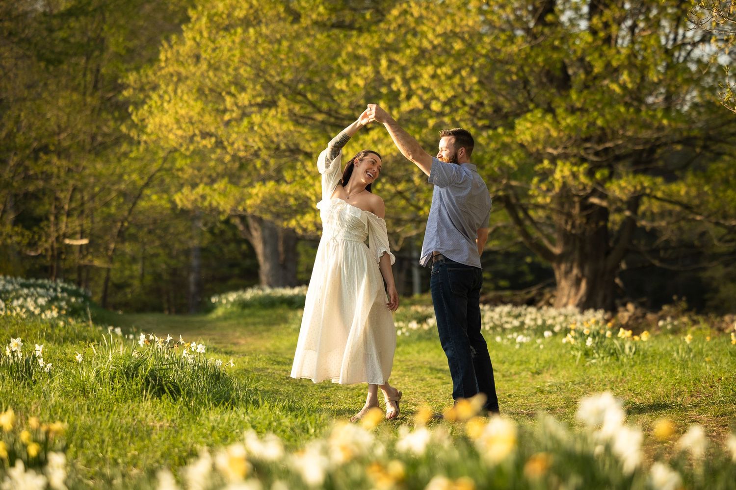 A couple dances in a sunlit meadow surrounded by golden autumn trees and warm evening light.