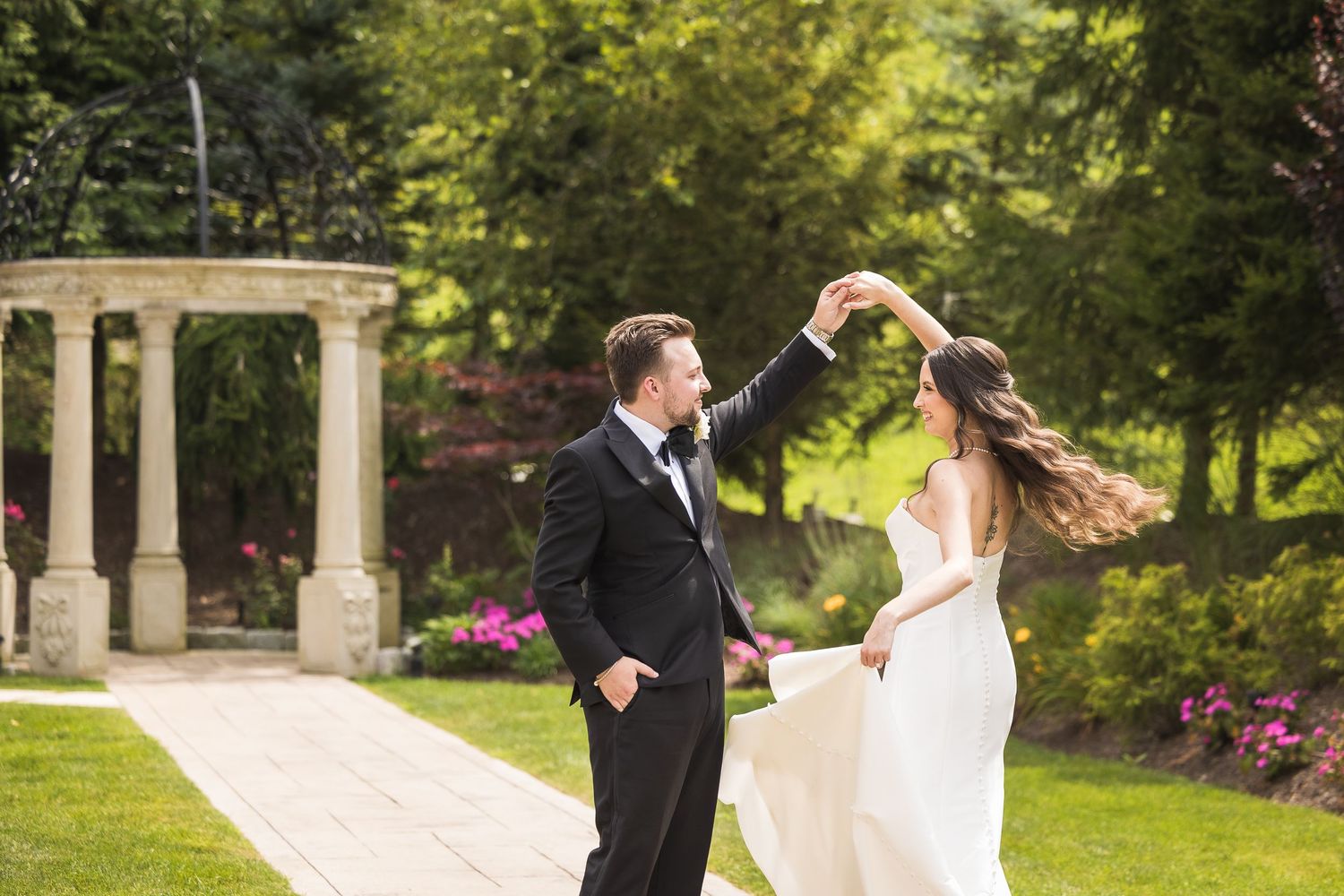 Romantic outdoor wedding photoshoot in a lush garden with stone columns.