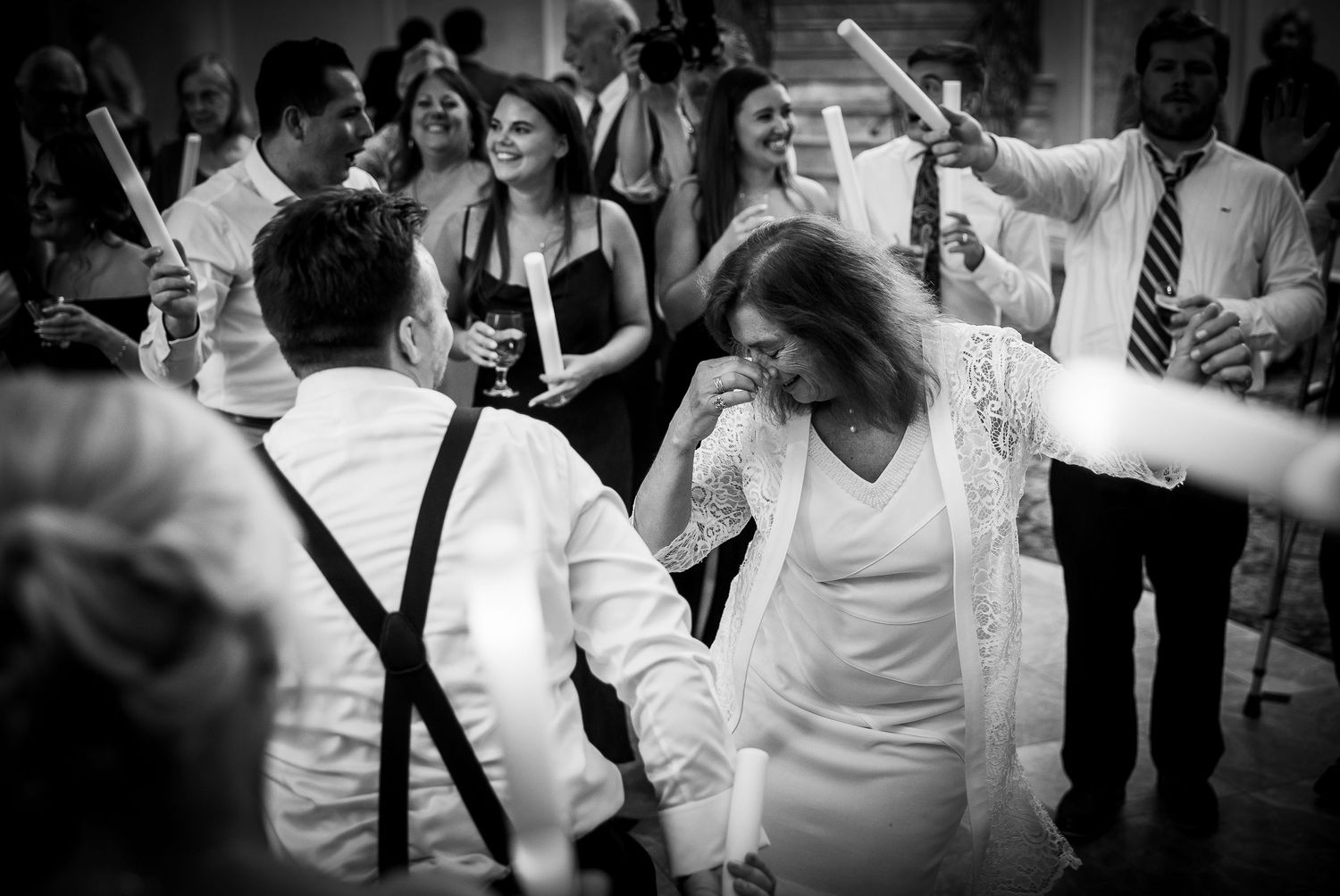 Black and white photo of wedding guests dancing energetically on the dance floor.