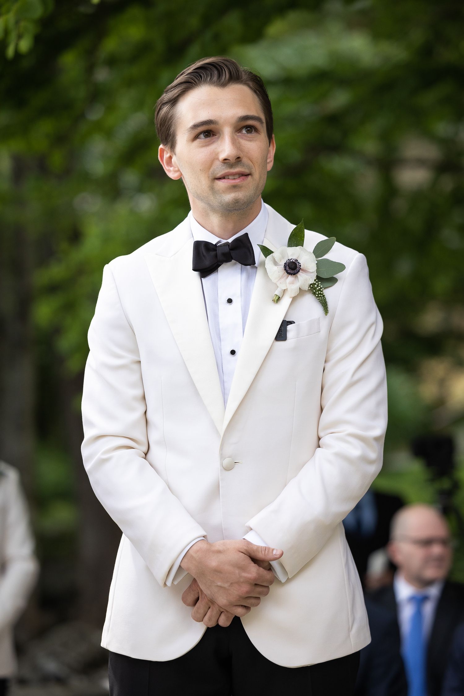 Groom in white dinner jacket with black bow tie and boutonniere.