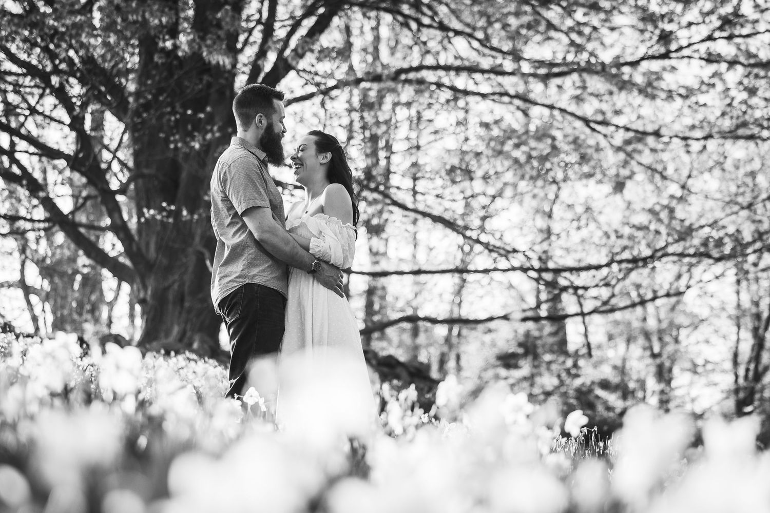 Black and white romantic wedding photos show couple embracing under trees in a dreamy forest setting.