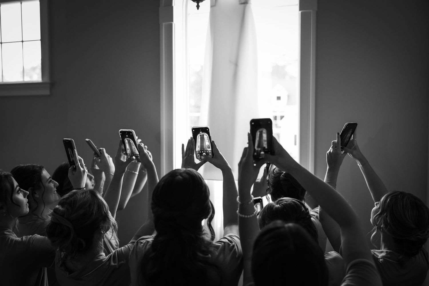 Silhouetted crowd raises hands in worship during a church service with sunlight streaming through windows.