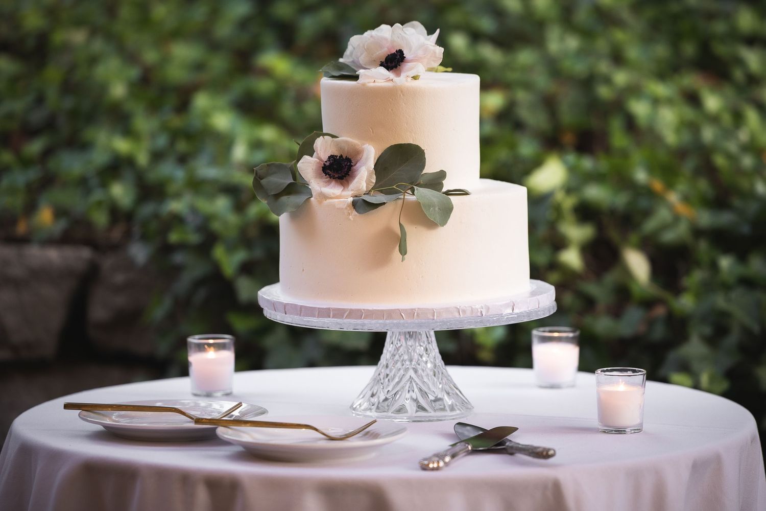Elegant white wedding cake decorated with delicate flowers on a classic cake stand.
