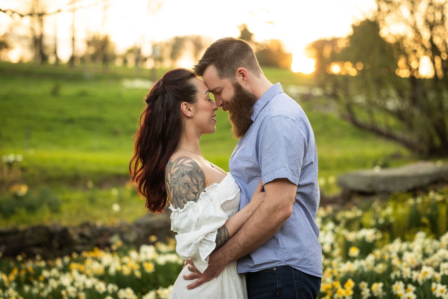 A couple embraces in a garden at sunset with blooming spring daffodils in the background.
