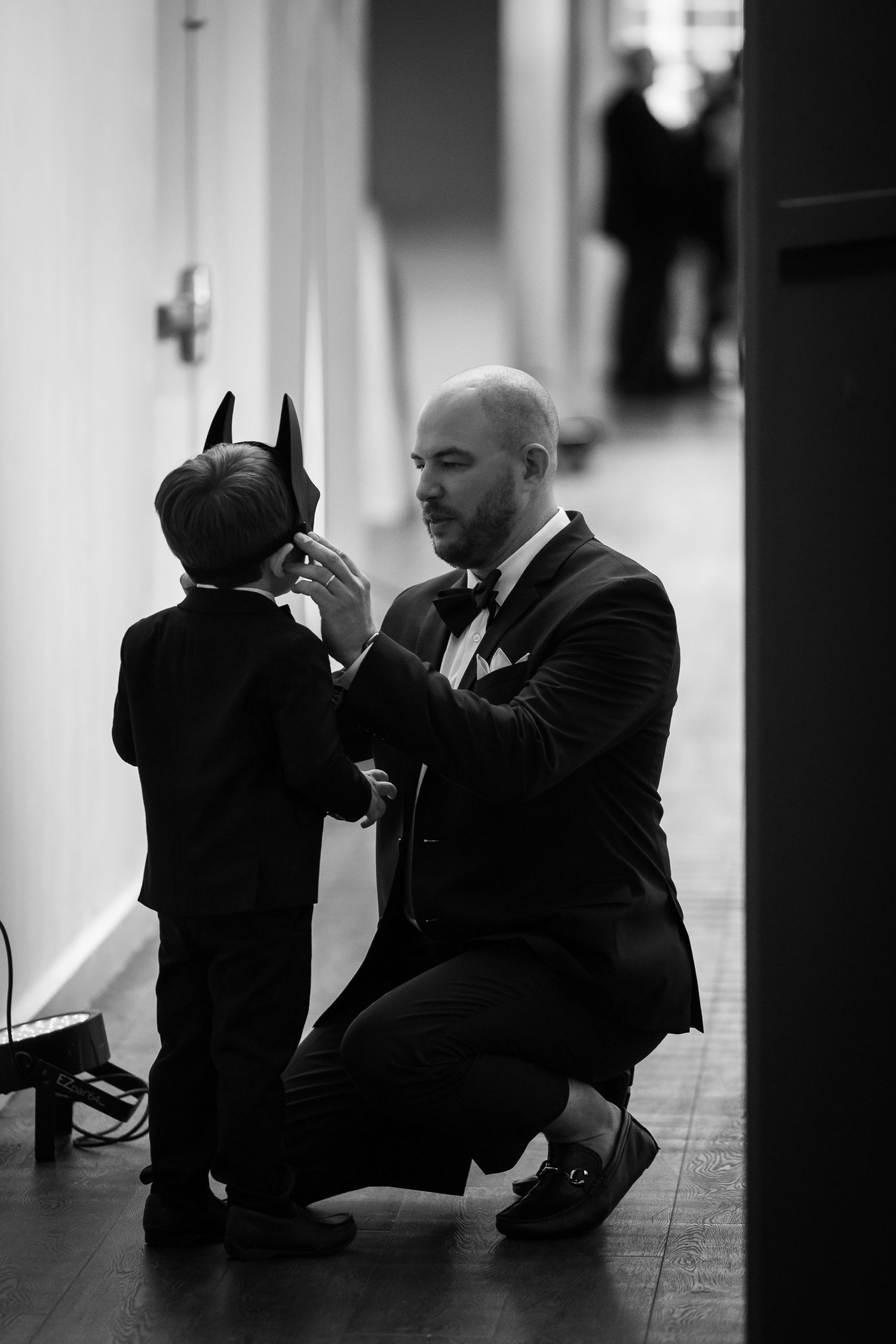 Black and white photo sequence showing a businessman in suit sitting on floor against wall in dark hallway.