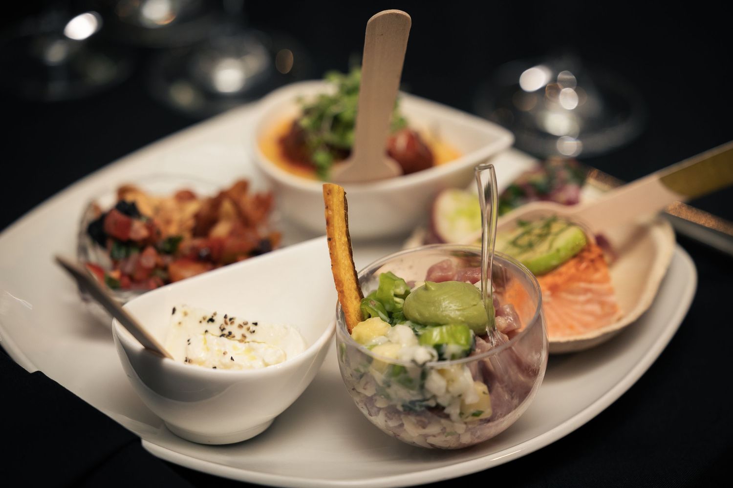 A series of elegant appetizer plates featuring various small bites and dips arranged on white ceramic dishes.