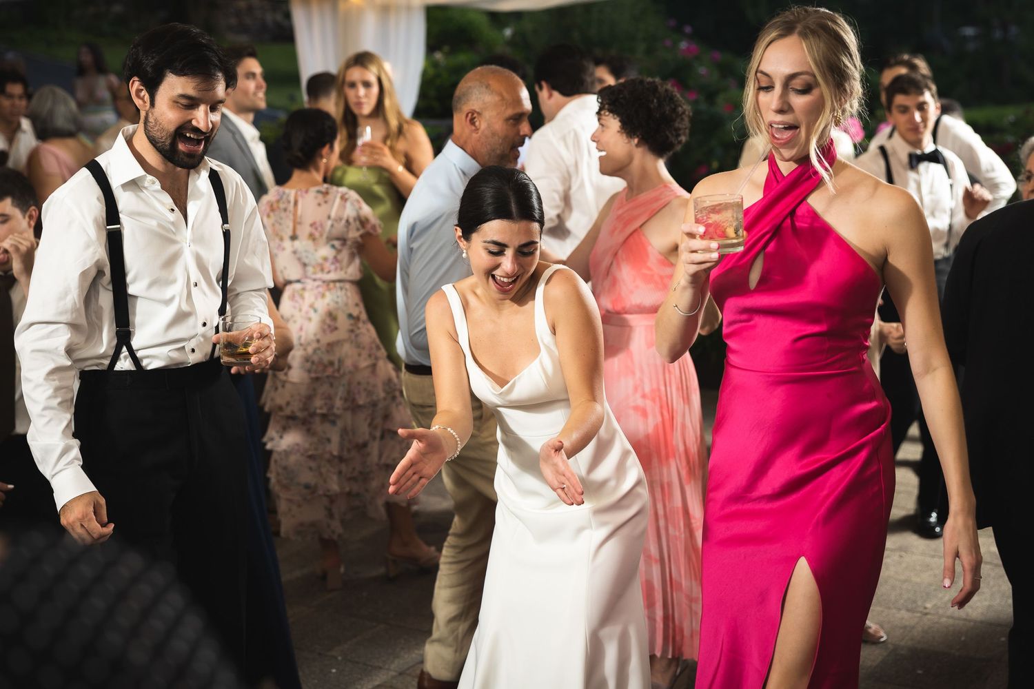 Lively wedding reception with bride and guests dancing and celebrating in formal attire.
