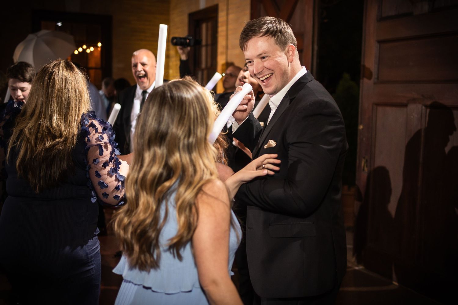 Wedding celebration captured in a dimly lit reception venue with guests dancing.