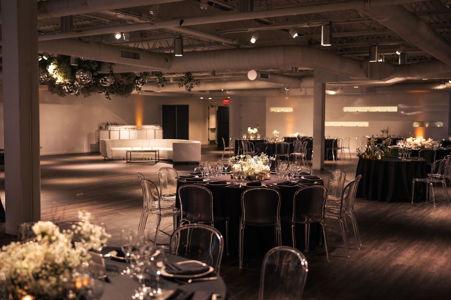 Elegant banquet hall setup with round tables, chairs, and dramatic lighting creating an upscale event atmosphere.