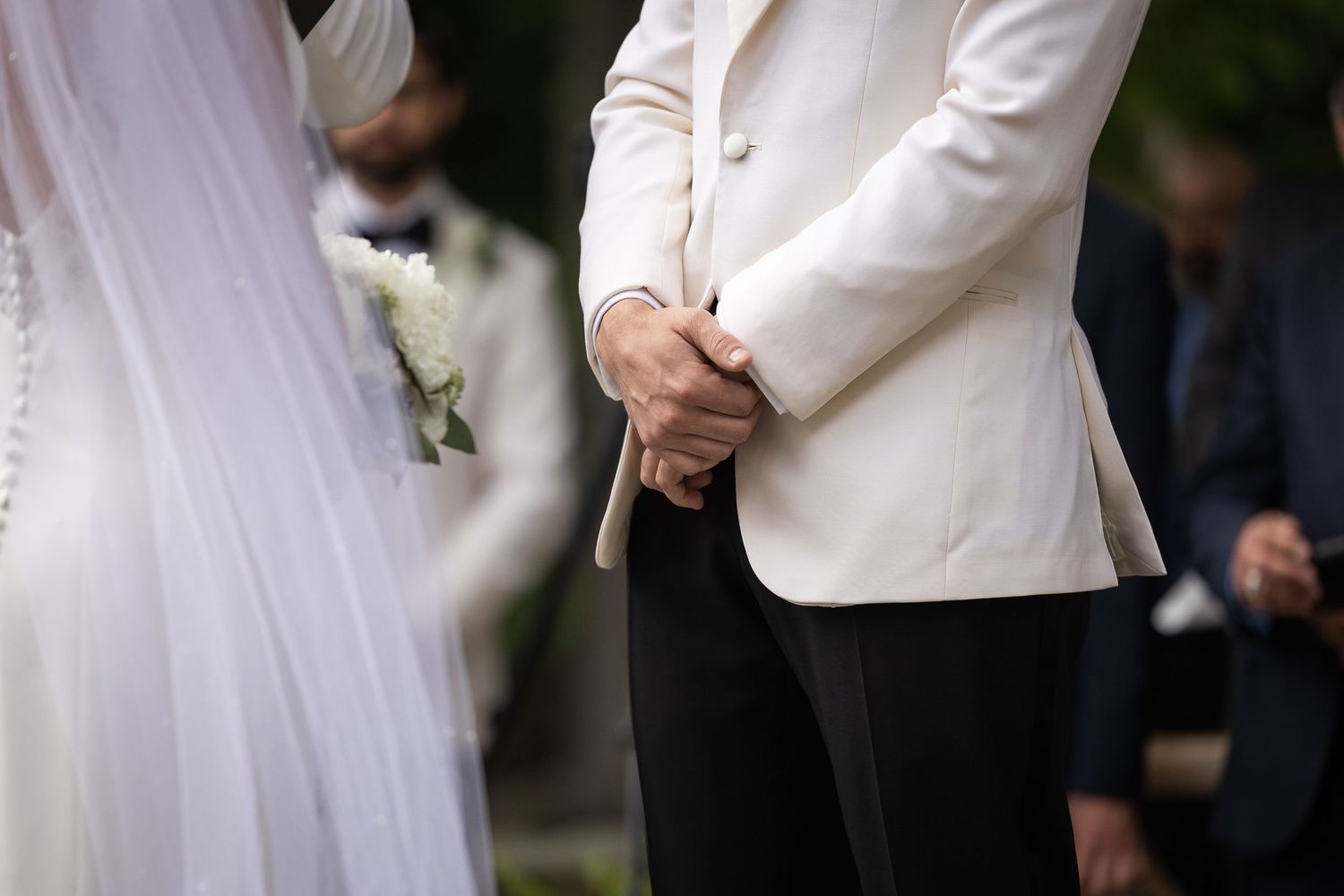 Wedding ceremony details showing white formal attire and outdoor setting.