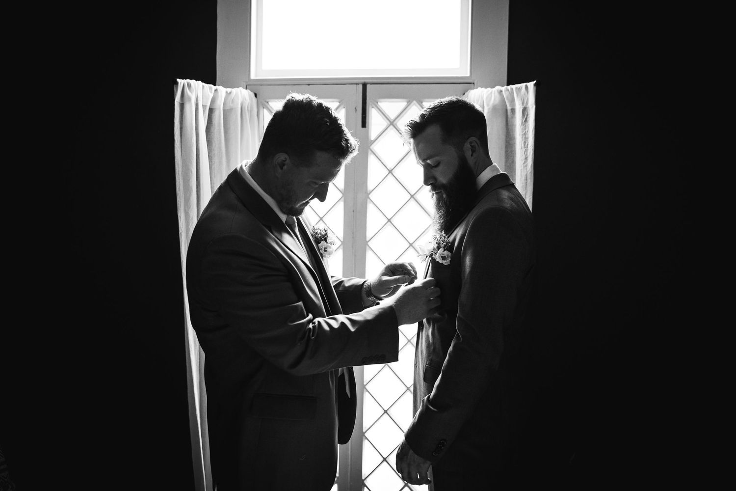 Black and white silhouettes of two people in conversation by a window.