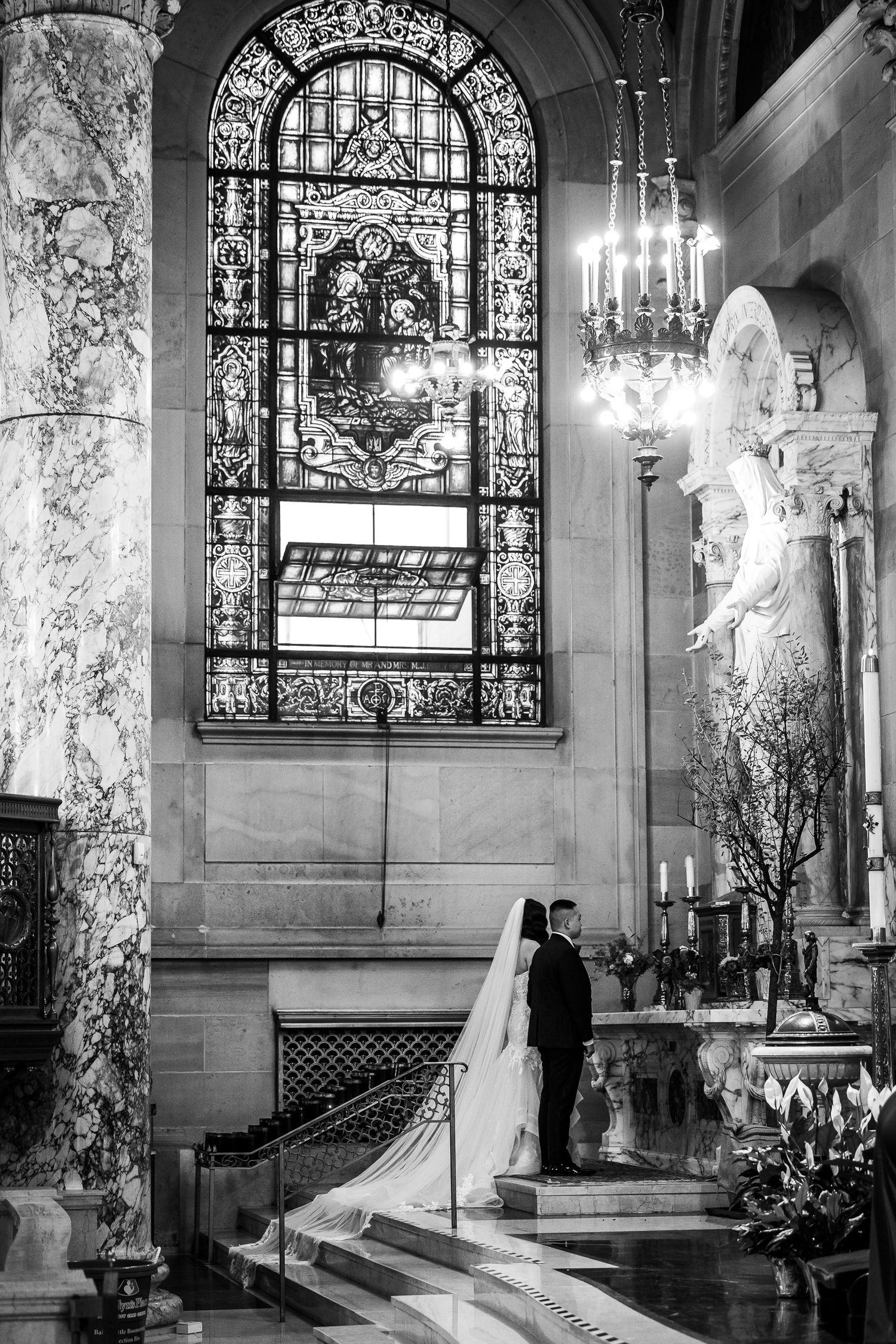 Elegant church interior with stained glass windows and marble columns during ceremony.