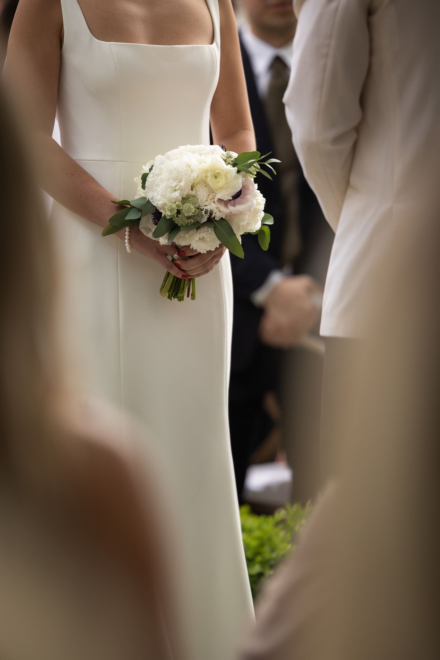 Elegant white bouquets held against simple white wedding dresses.