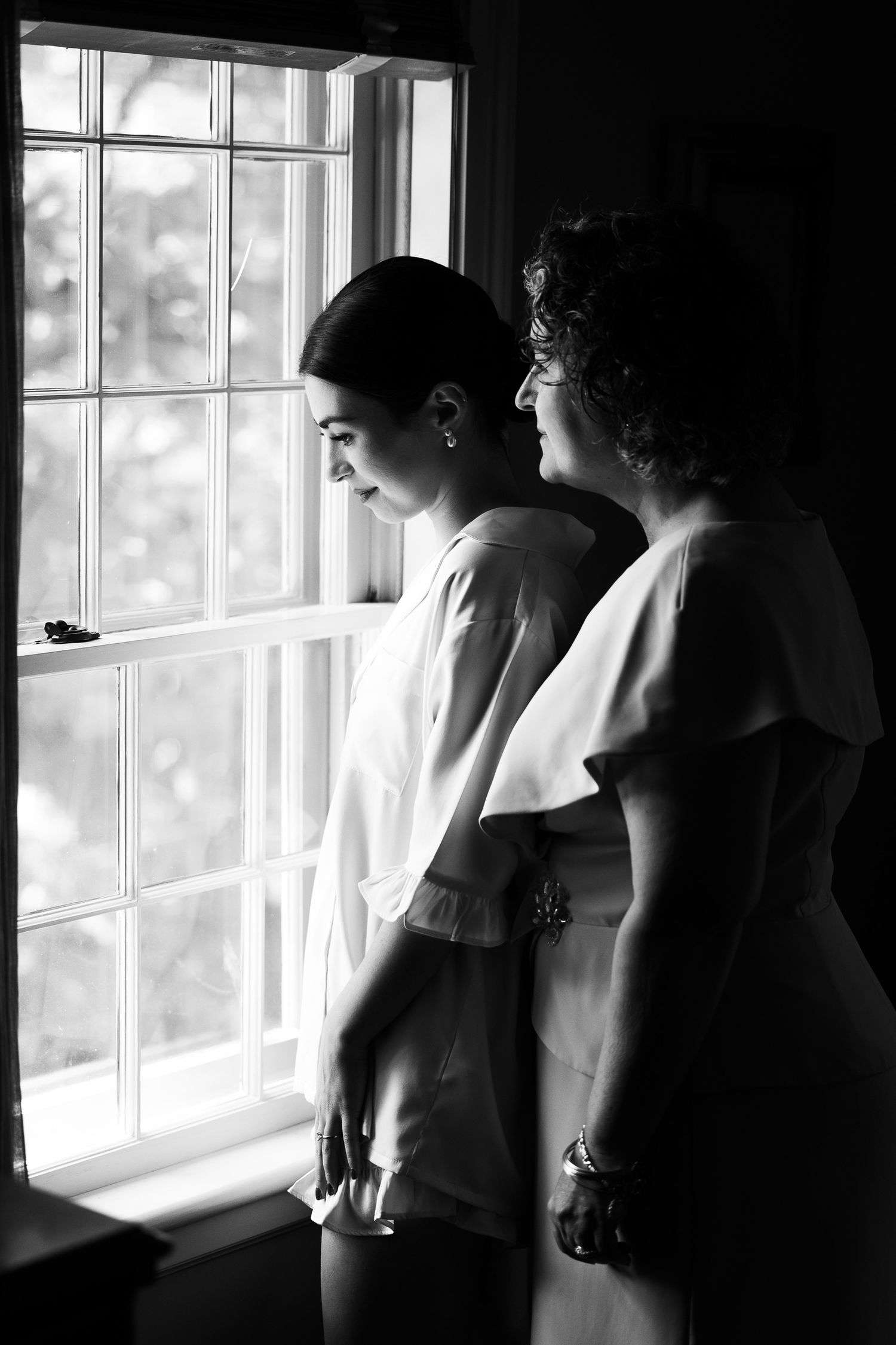 Silhouettes by window creating dramatic black and white composition.