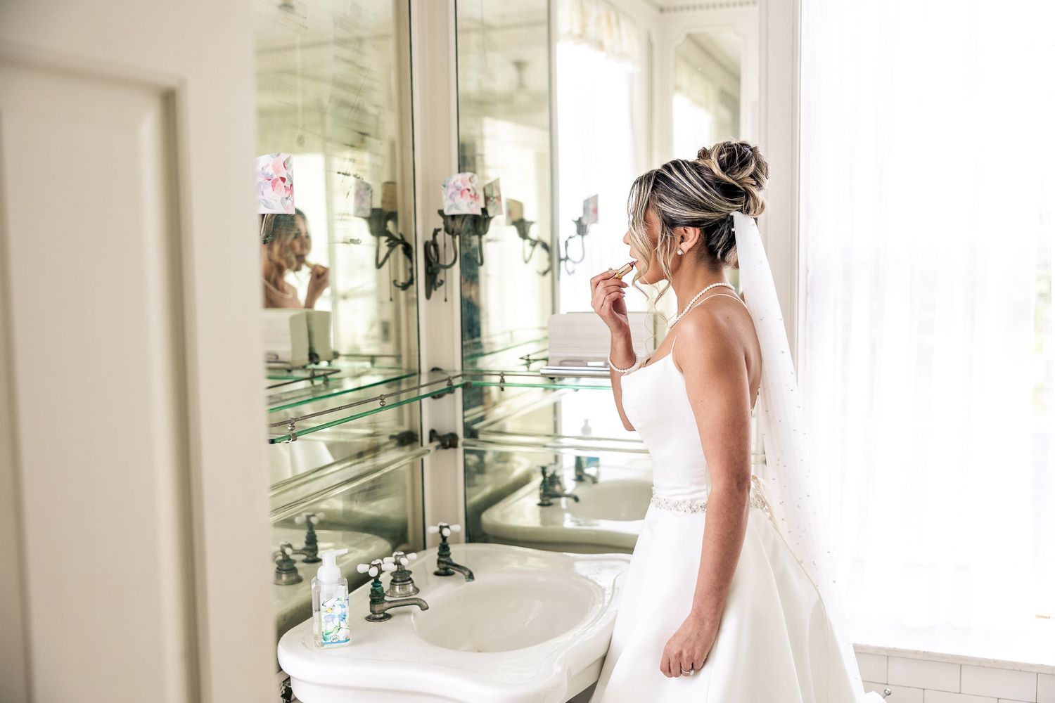 Bride checks final details in mirror-lined dressing room.