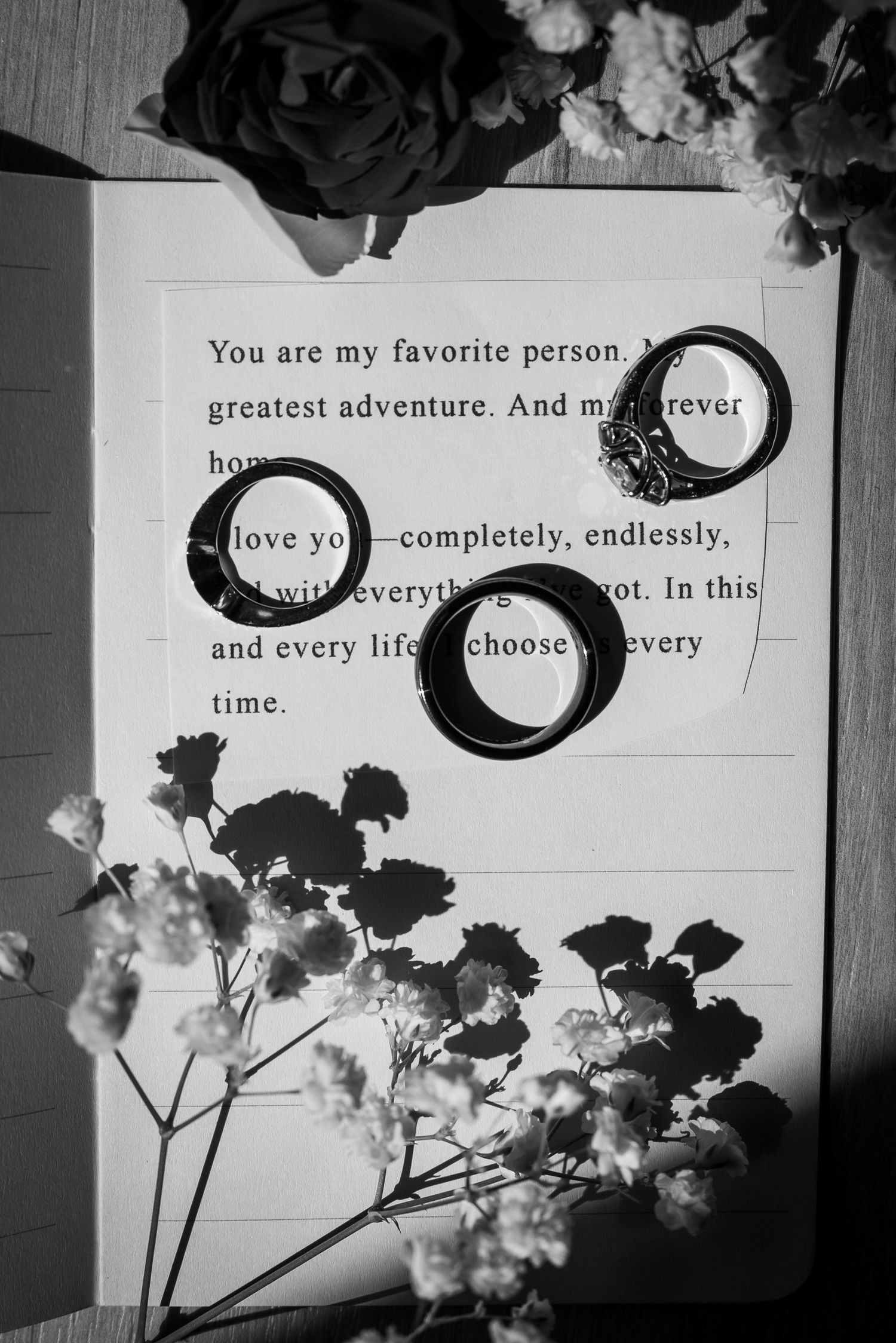 Black and white photo of love letter text with delicate white flowers against a light background.