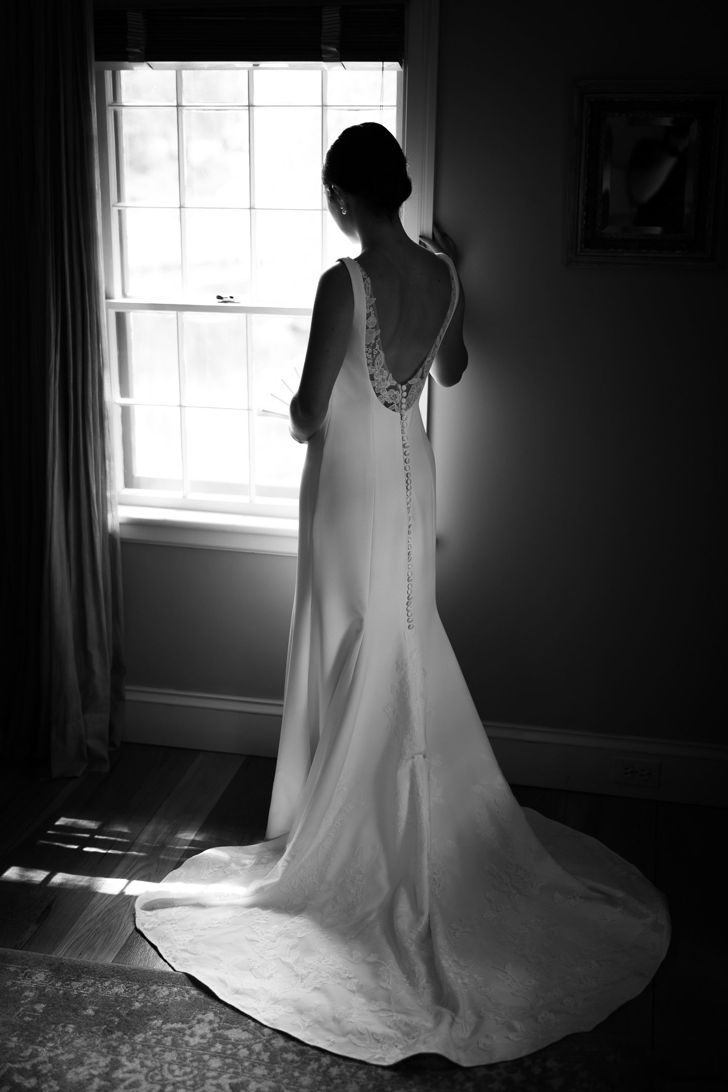 Dramatic black and white silhouette of a wedding dress in a sunlit room.