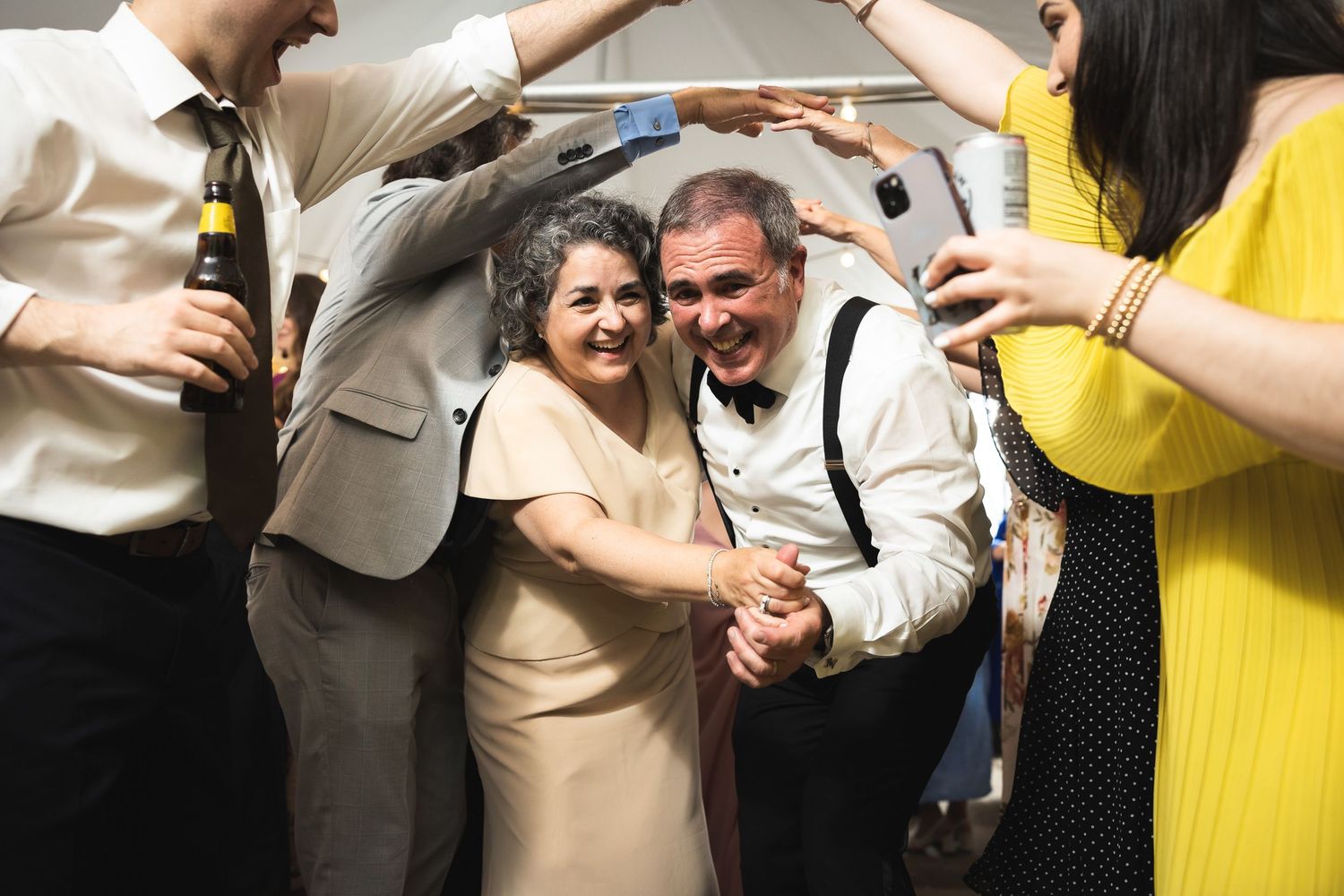 Wedding guests dancing and celebrating at an indoor reception.