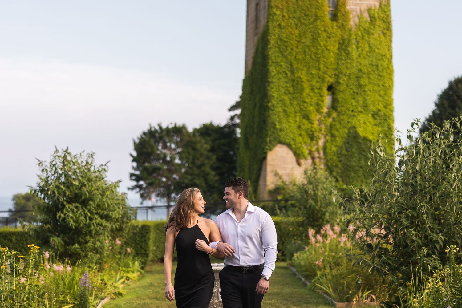 A couple shares a romantic moment in front of an ivy-covered wall during their engagement photoshoot.